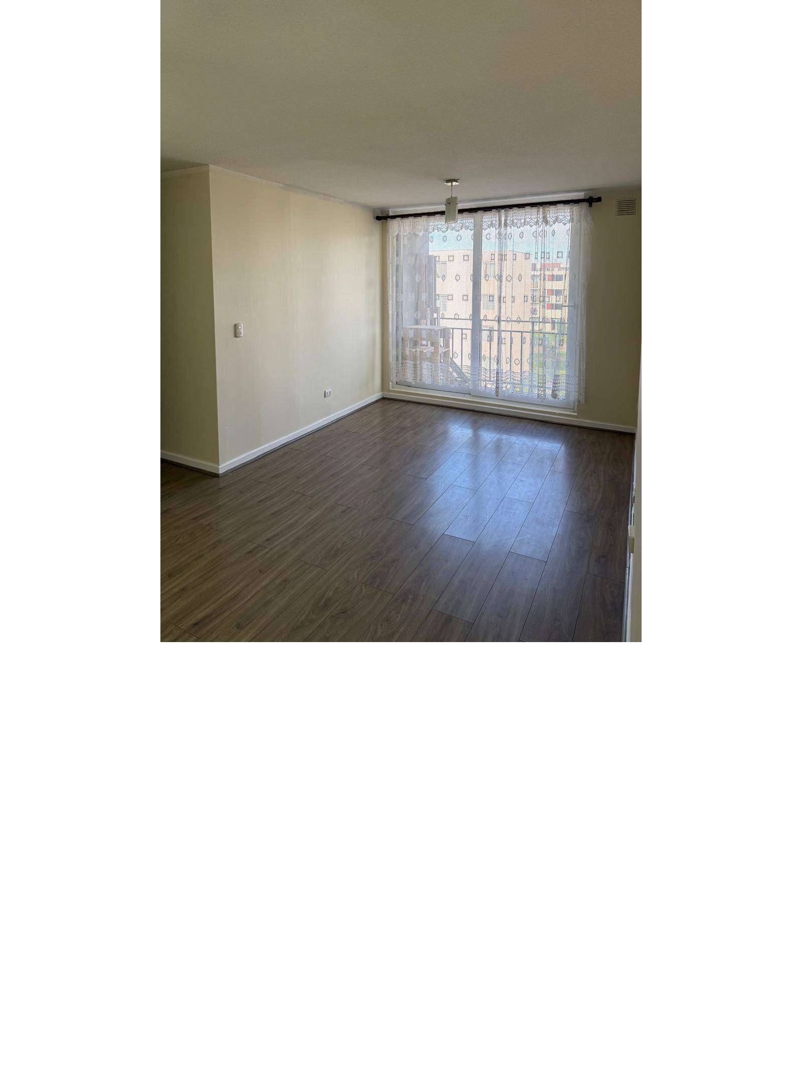 Living amplio con piso flotante y ventanal con cortinas.