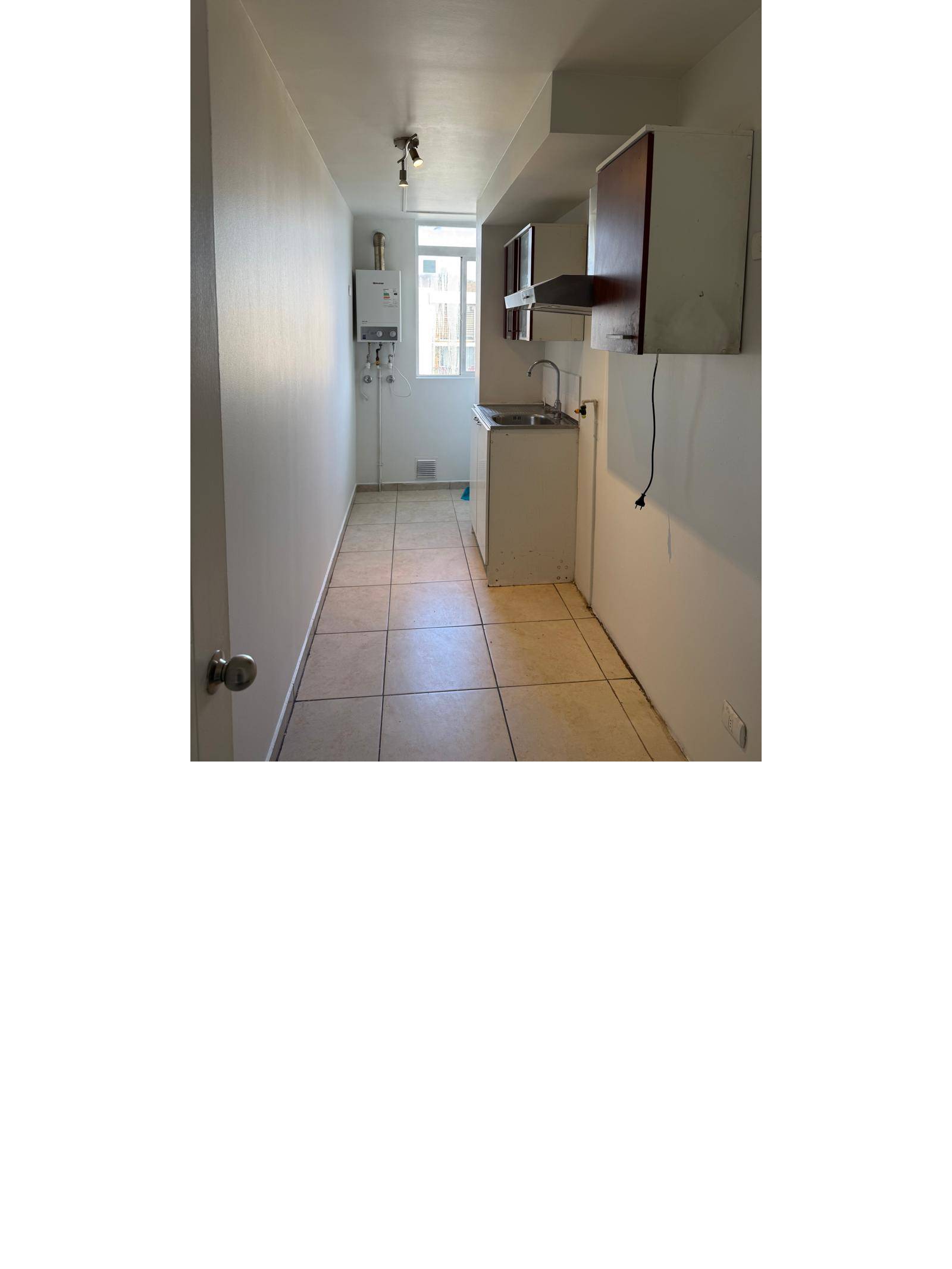 Cocina alargada con muebles, campana, calefón y ventana.