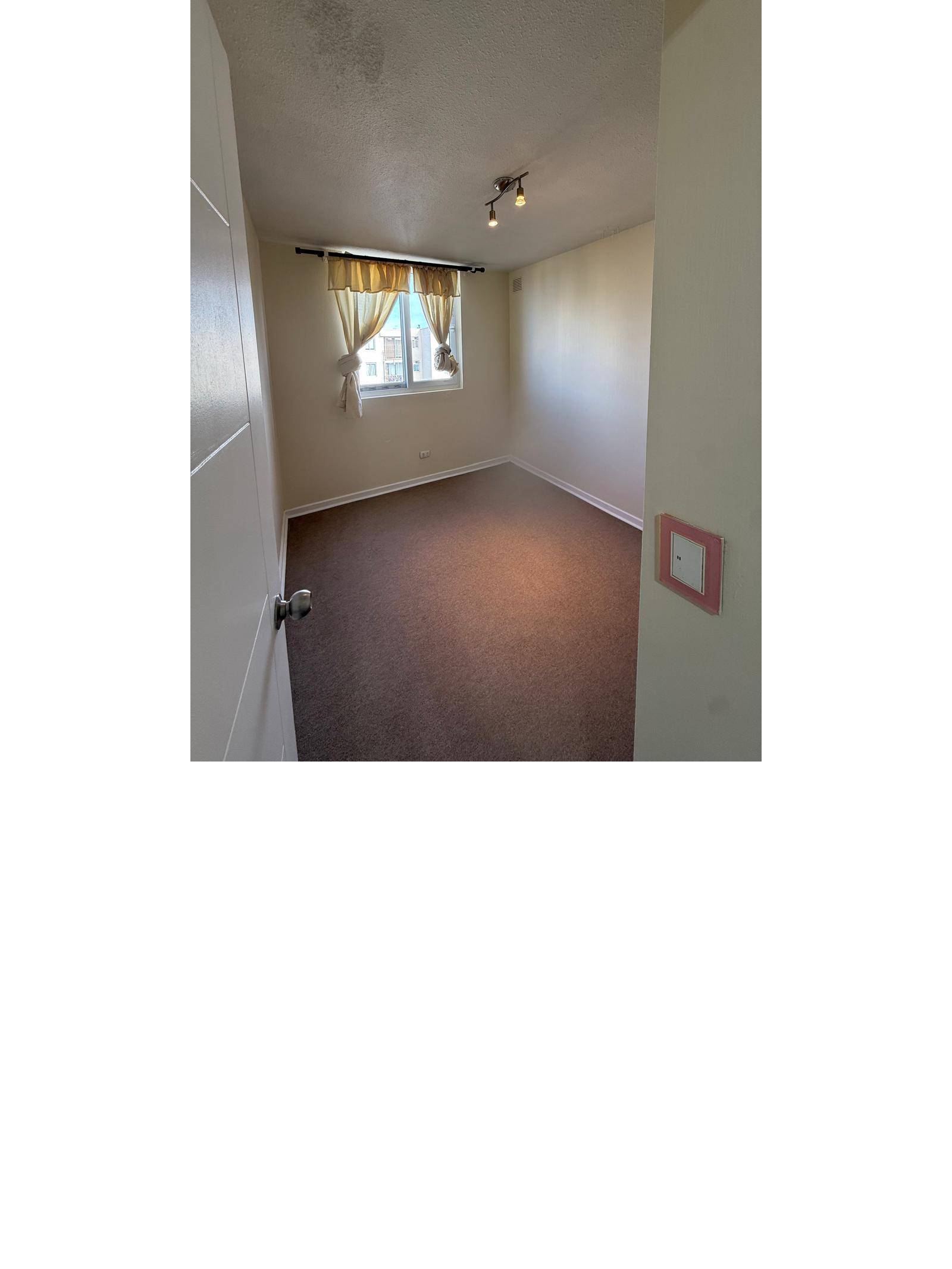 Dormitorio con piso alfombrado, ventana y cortinas claras.