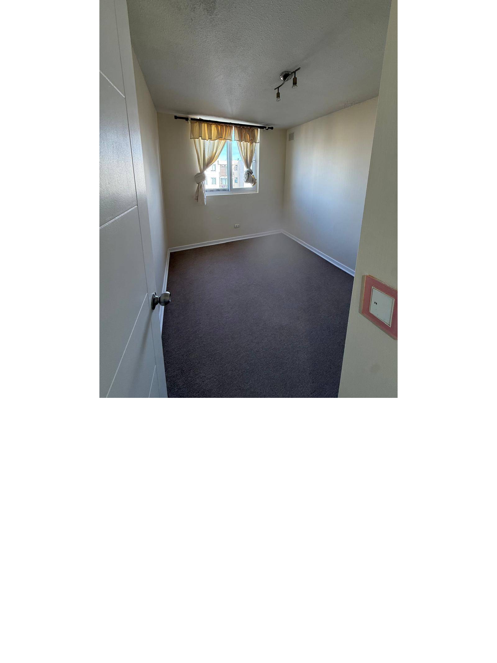 Dormitorio alfombrado visto desde la puerta de ingreso.