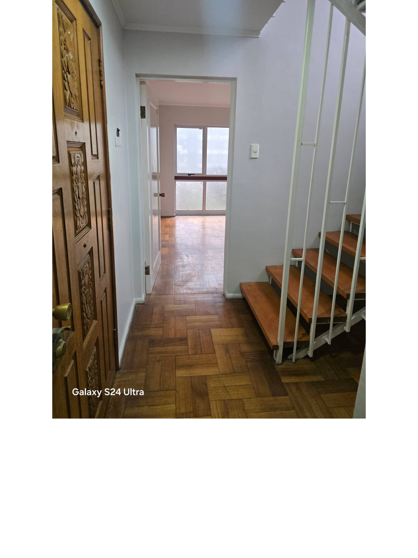 Hall de acceso con puerta de madera y escalera