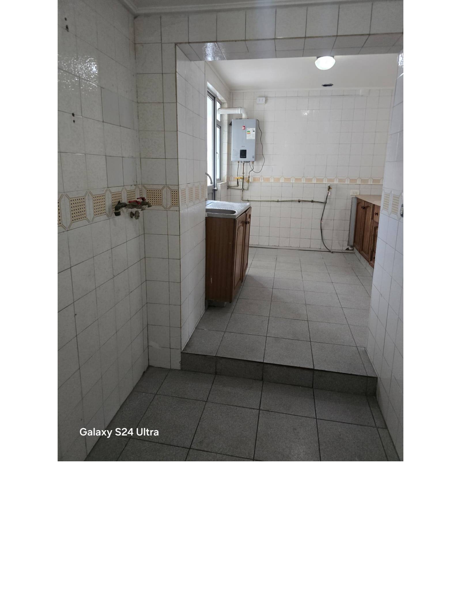 Cocina con azulejos blancos mueble lavaplatos y calefón