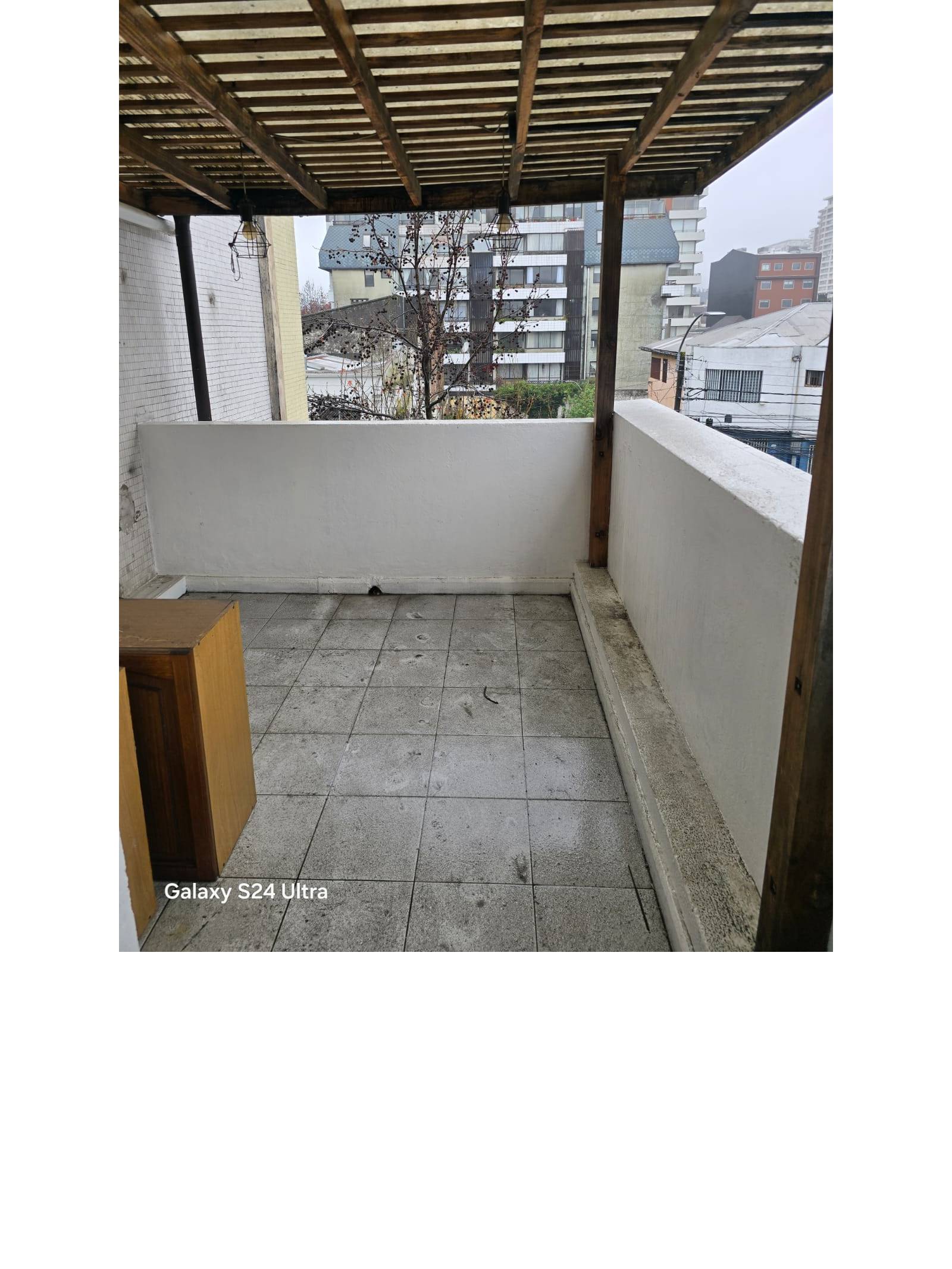 Terraza techada con pérgola de madera y vista urbana