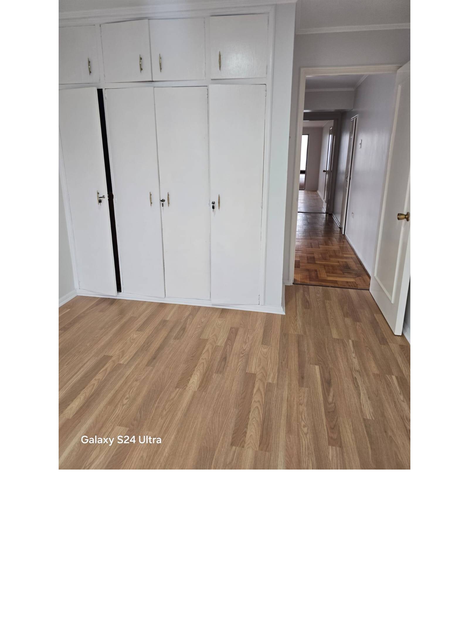 Dormitorio con clóset empotrado blanco y piso flotante