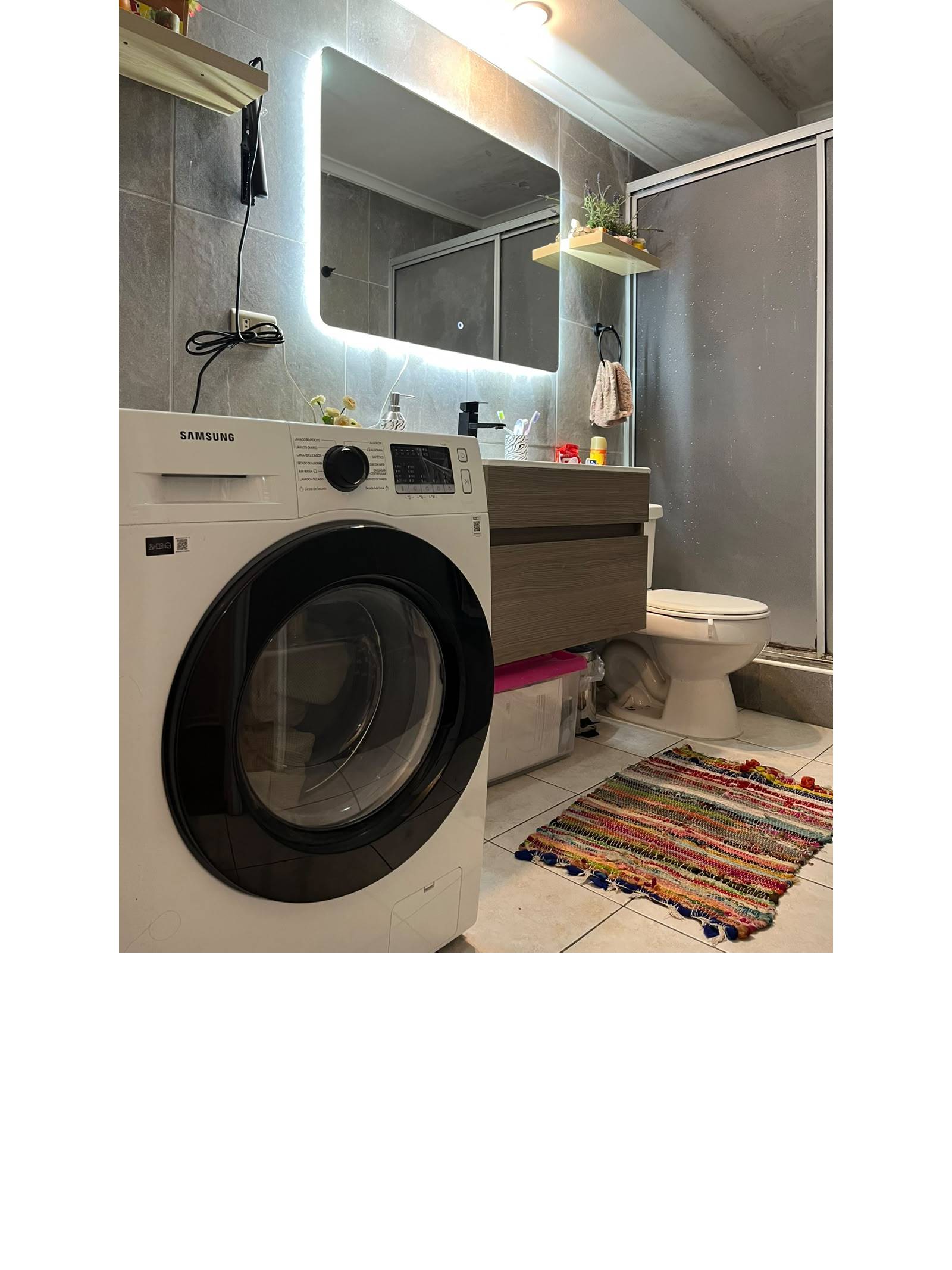 Baño con vanitorio moderno, espejo iluminado, ducha y lavadora