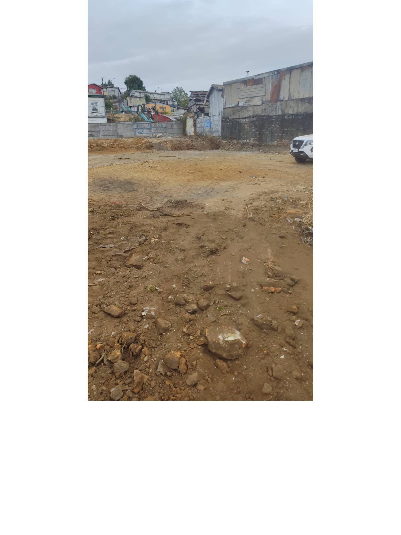 Suelo de tierra en terreno con muro y construcciones posteriores