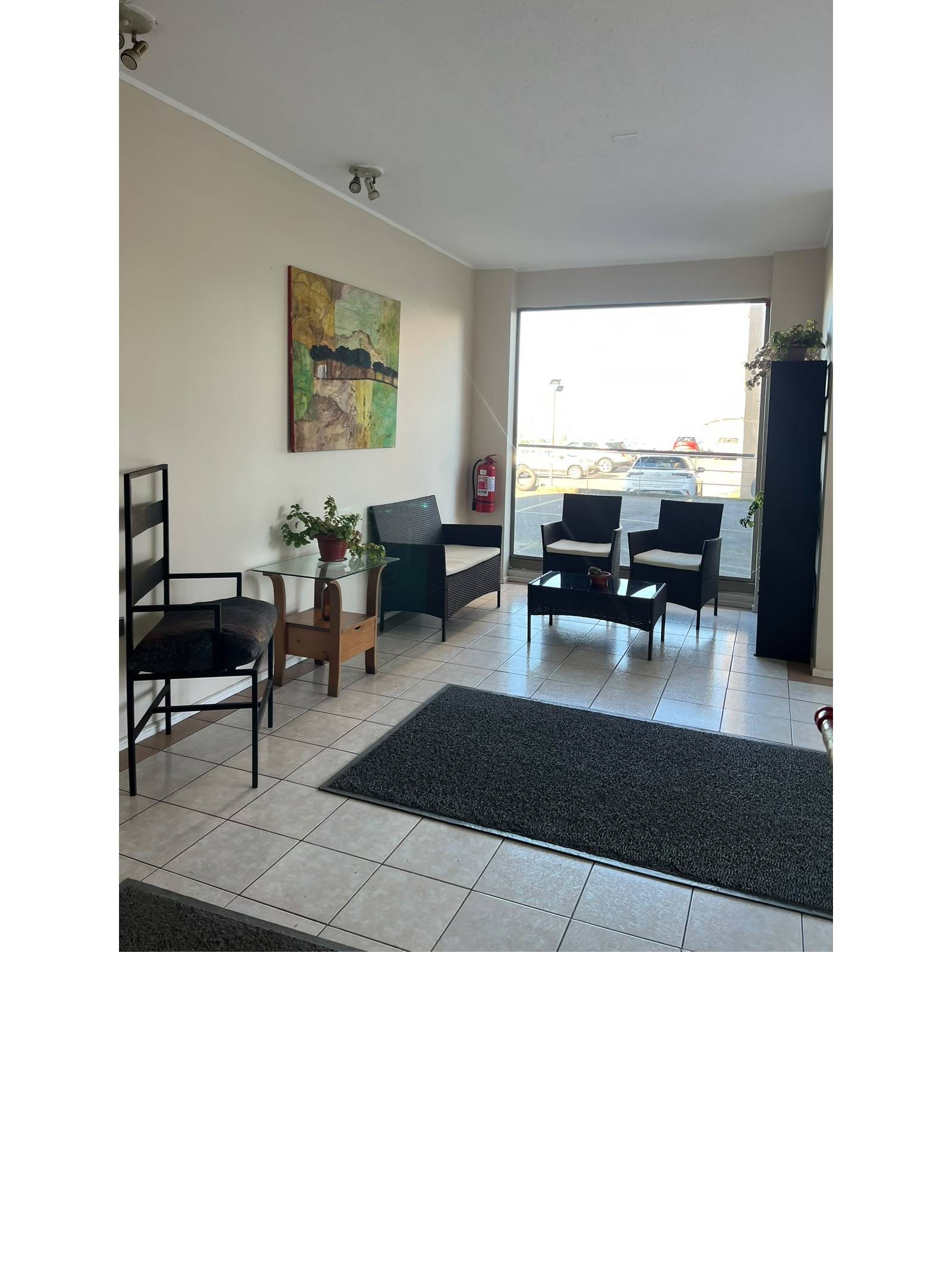 Sala de espera y recepción en edificio con sillones oscuros.