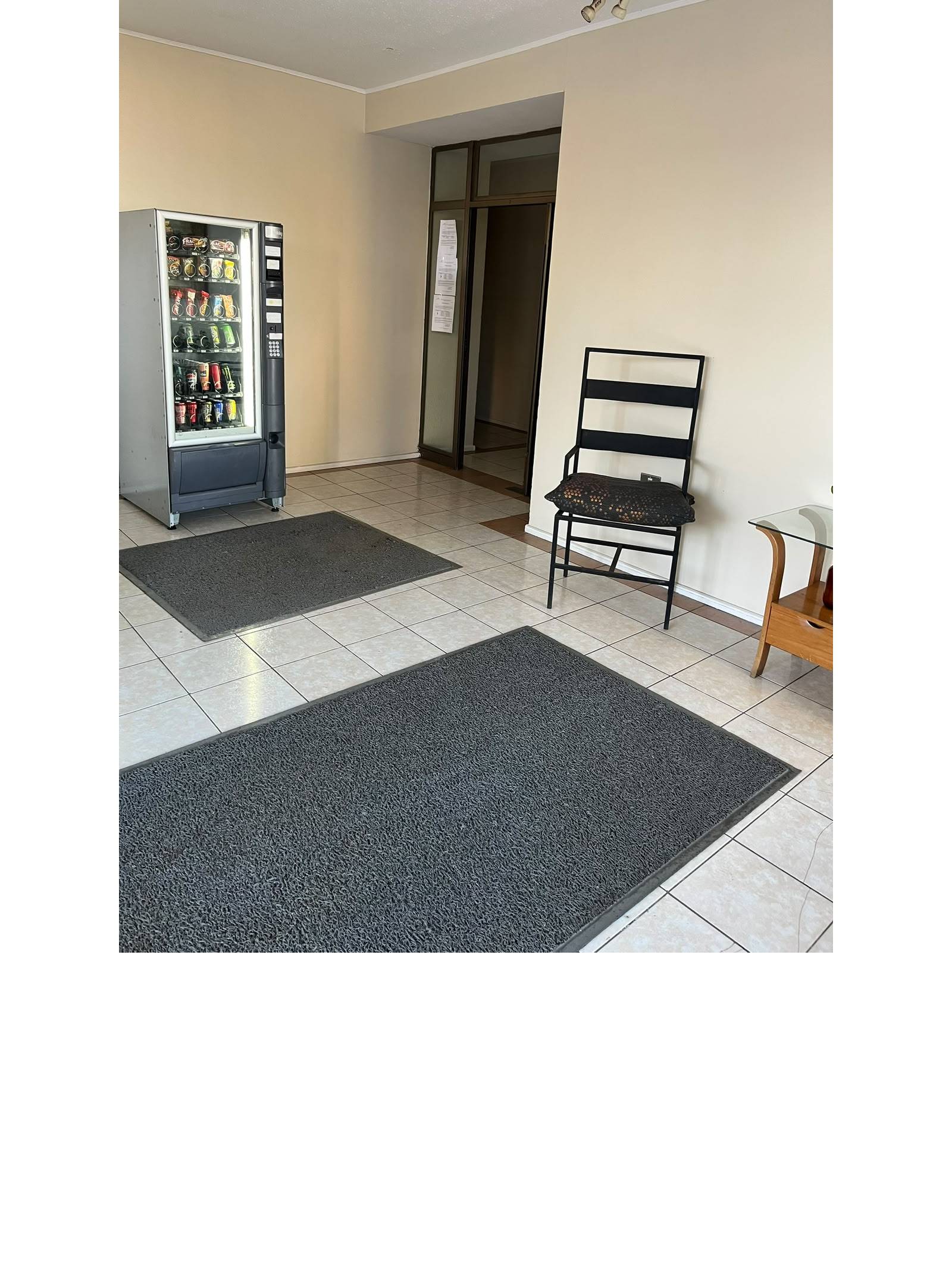 Acceso común con máquina expendedora y silla de espera.