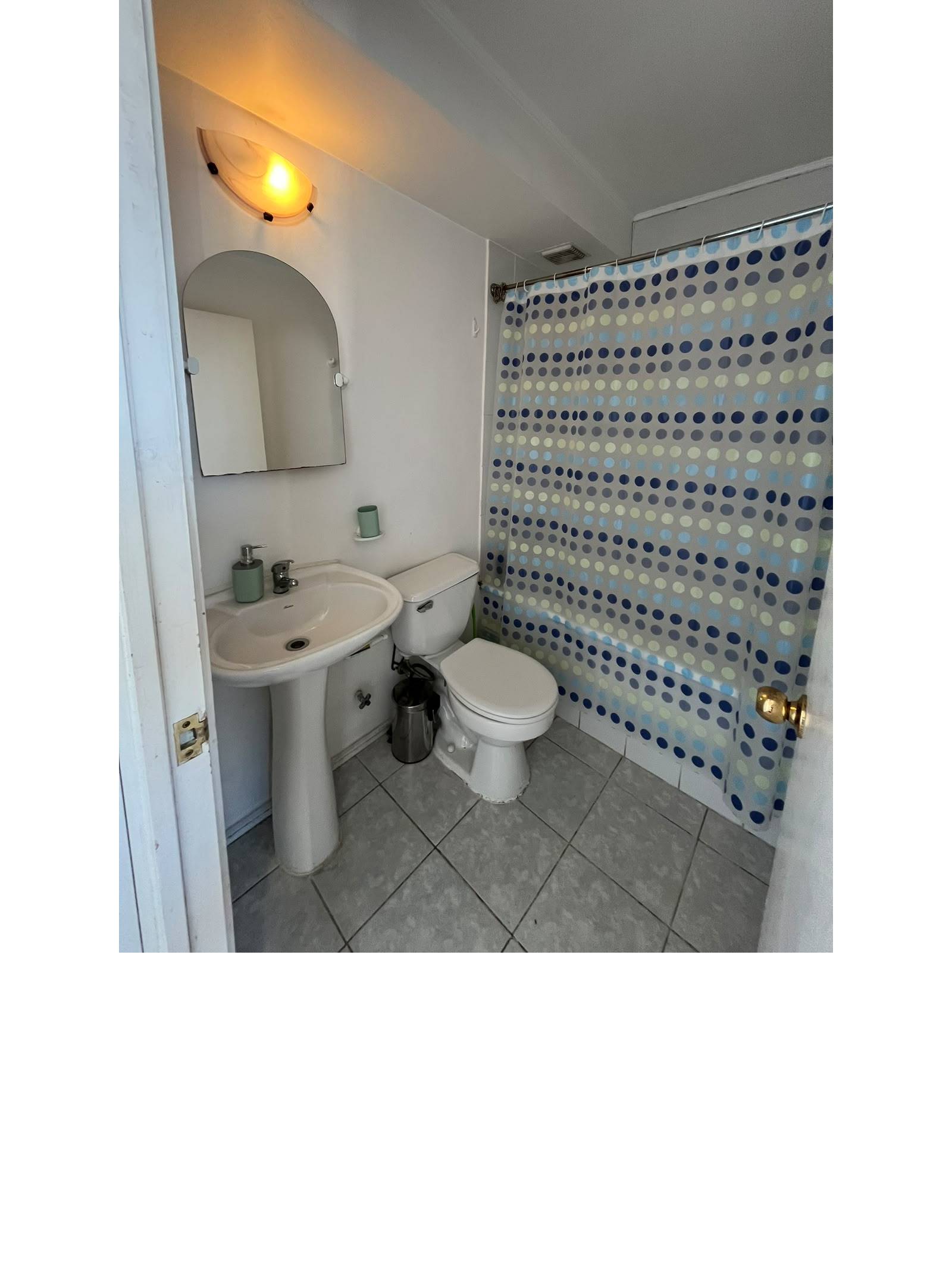 Baño con lavamanos de pedestal, inodoro y tina con cortina.