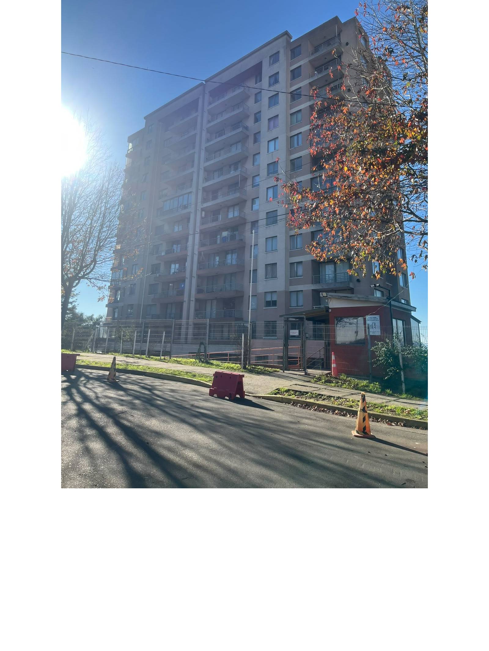 Edificio residencial en altura con acceso vehicular y caseta de seguridad.
