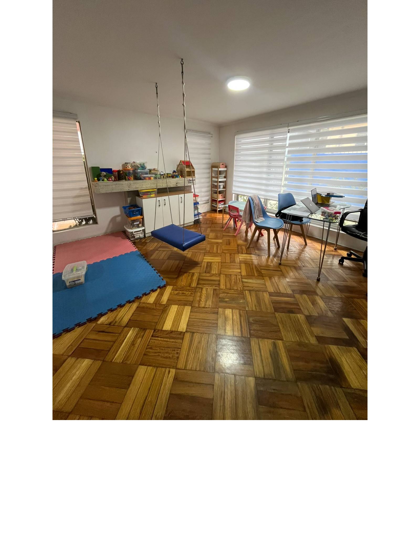 Sala terapéutica con piso de parquet, columpio y escritorio.