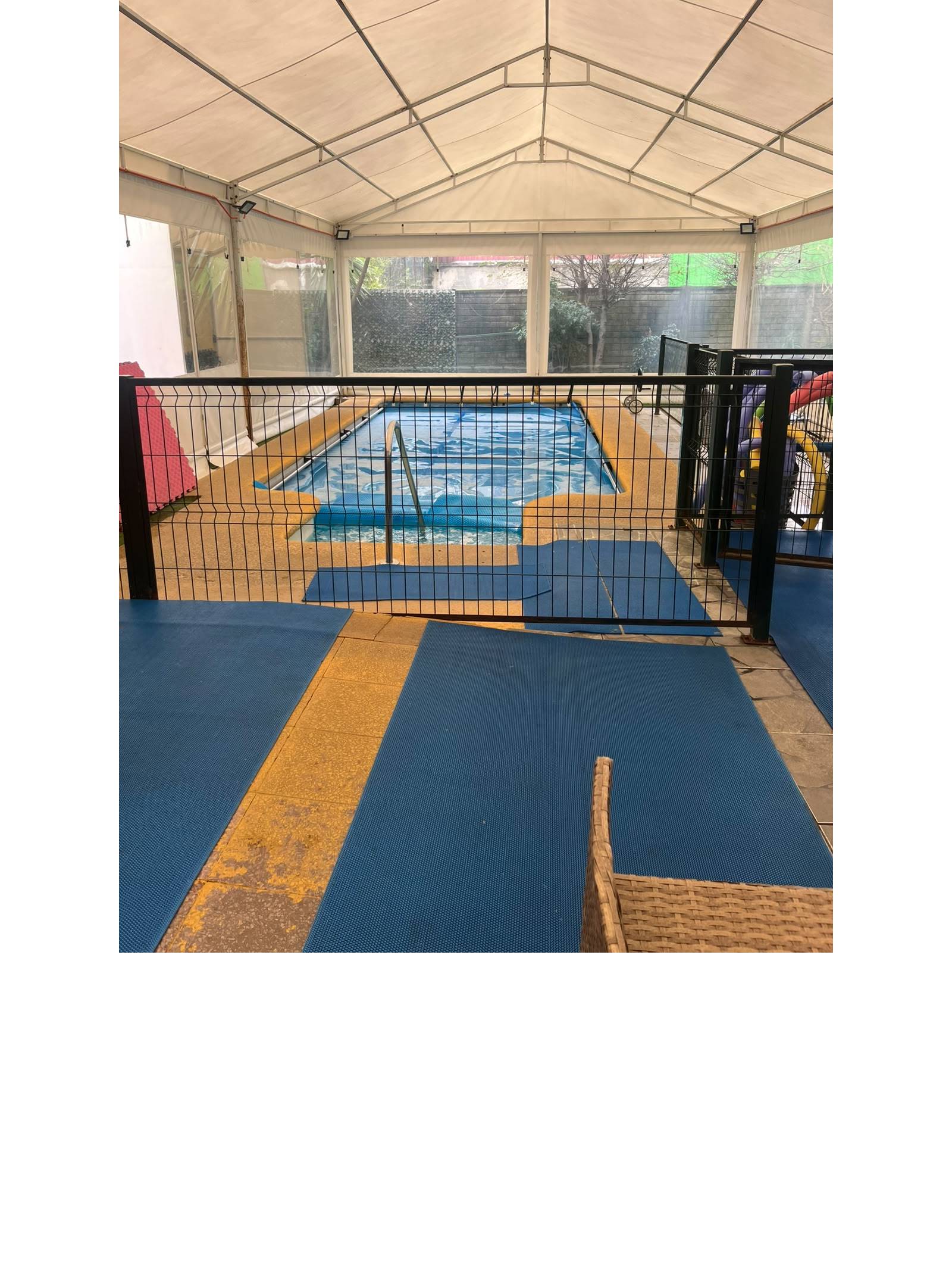 Piscina techada protegida con reja de seguridad perimetral.