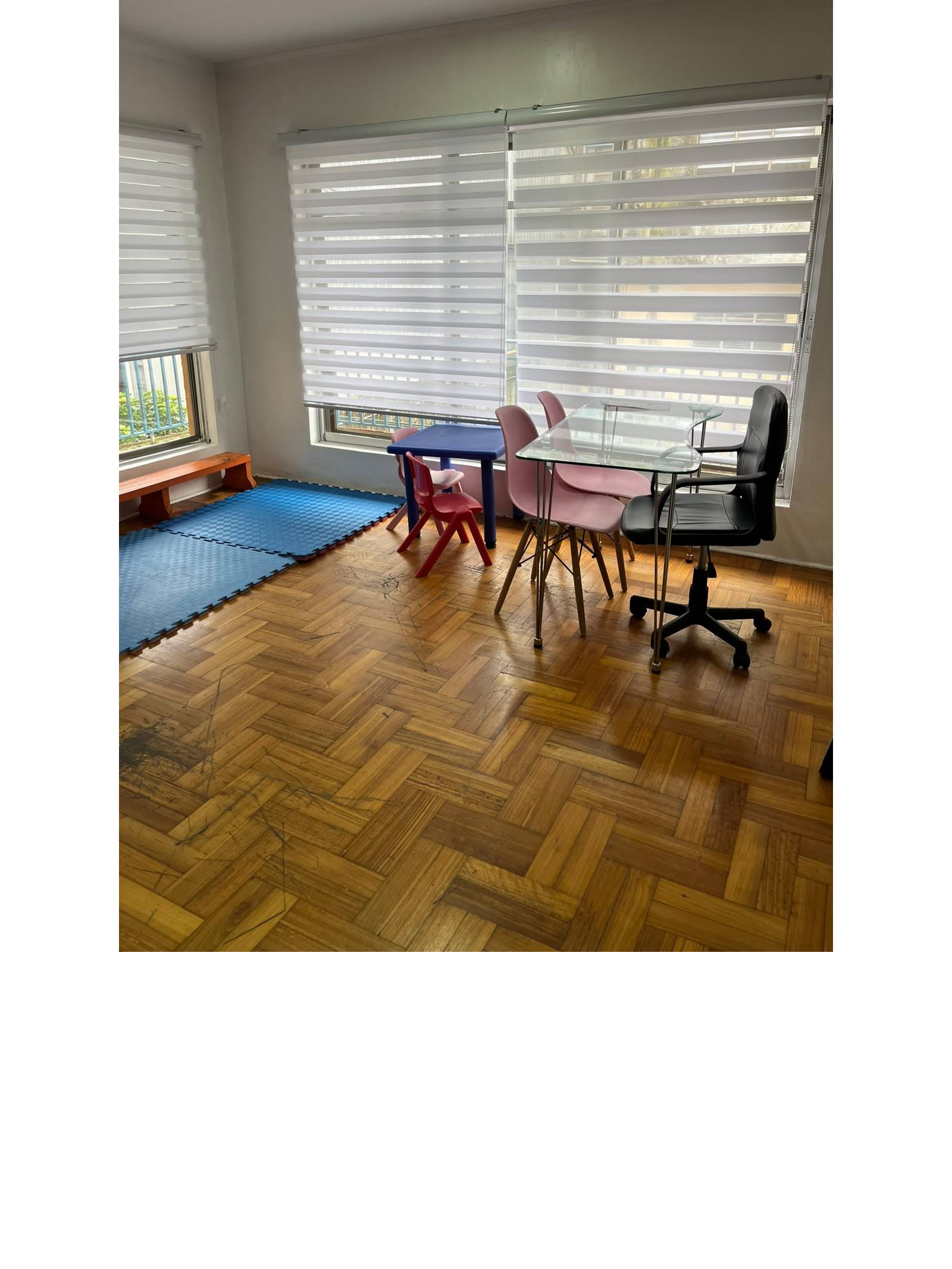 Habitación luminosa con piso de parquet y mesas de trabajo.