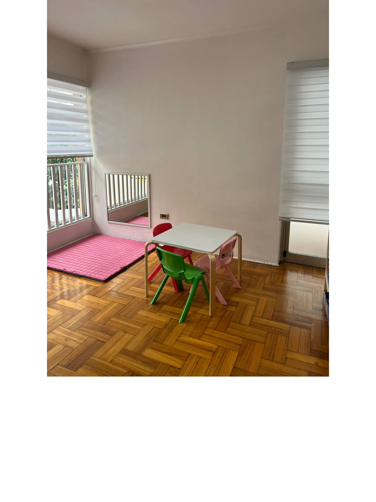 Dormitorio o sala de juegos con mesa infantil y espejo bajo.