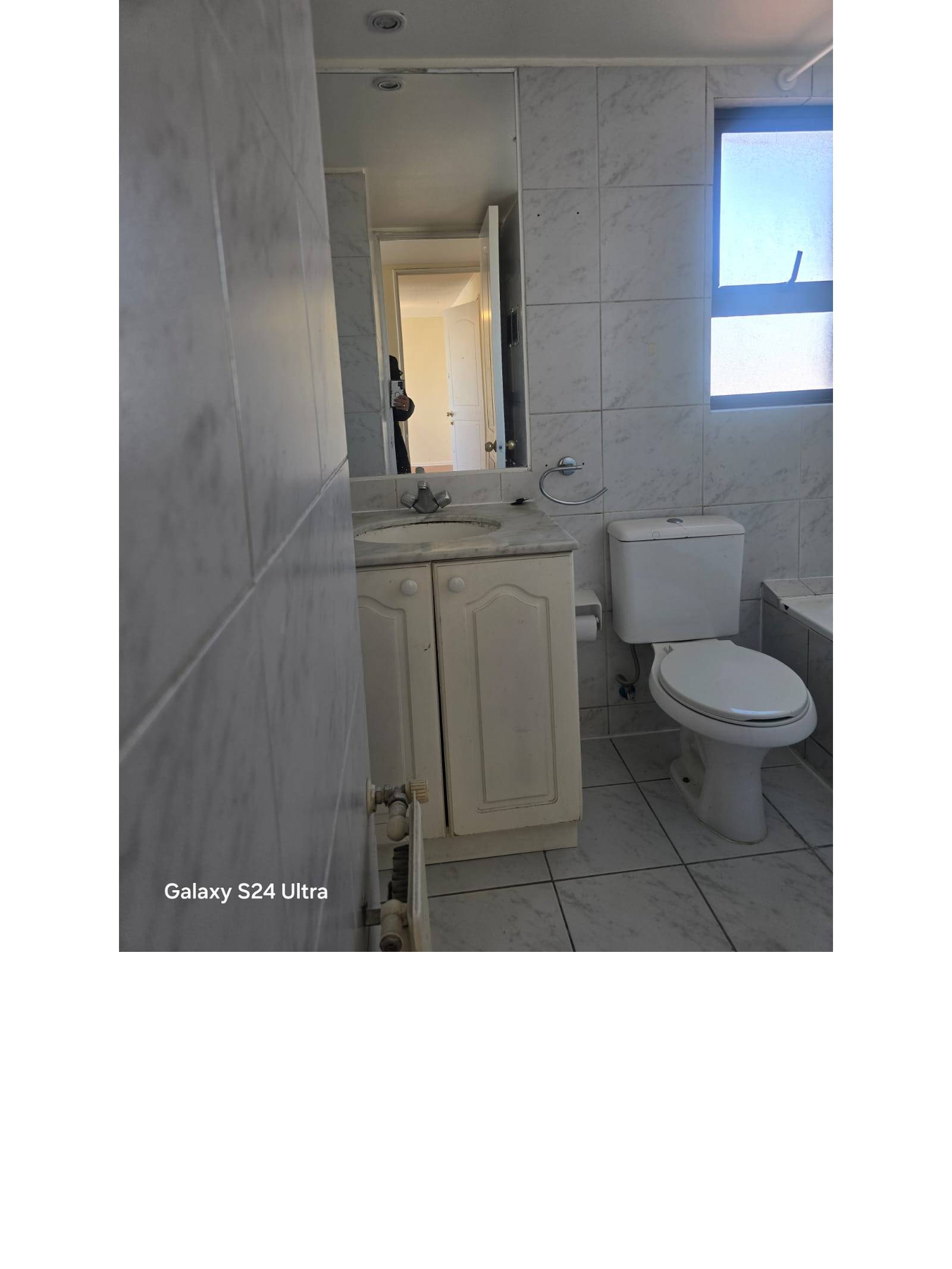 Baño con vanitorio blanco, inodoro y azulejos en muro