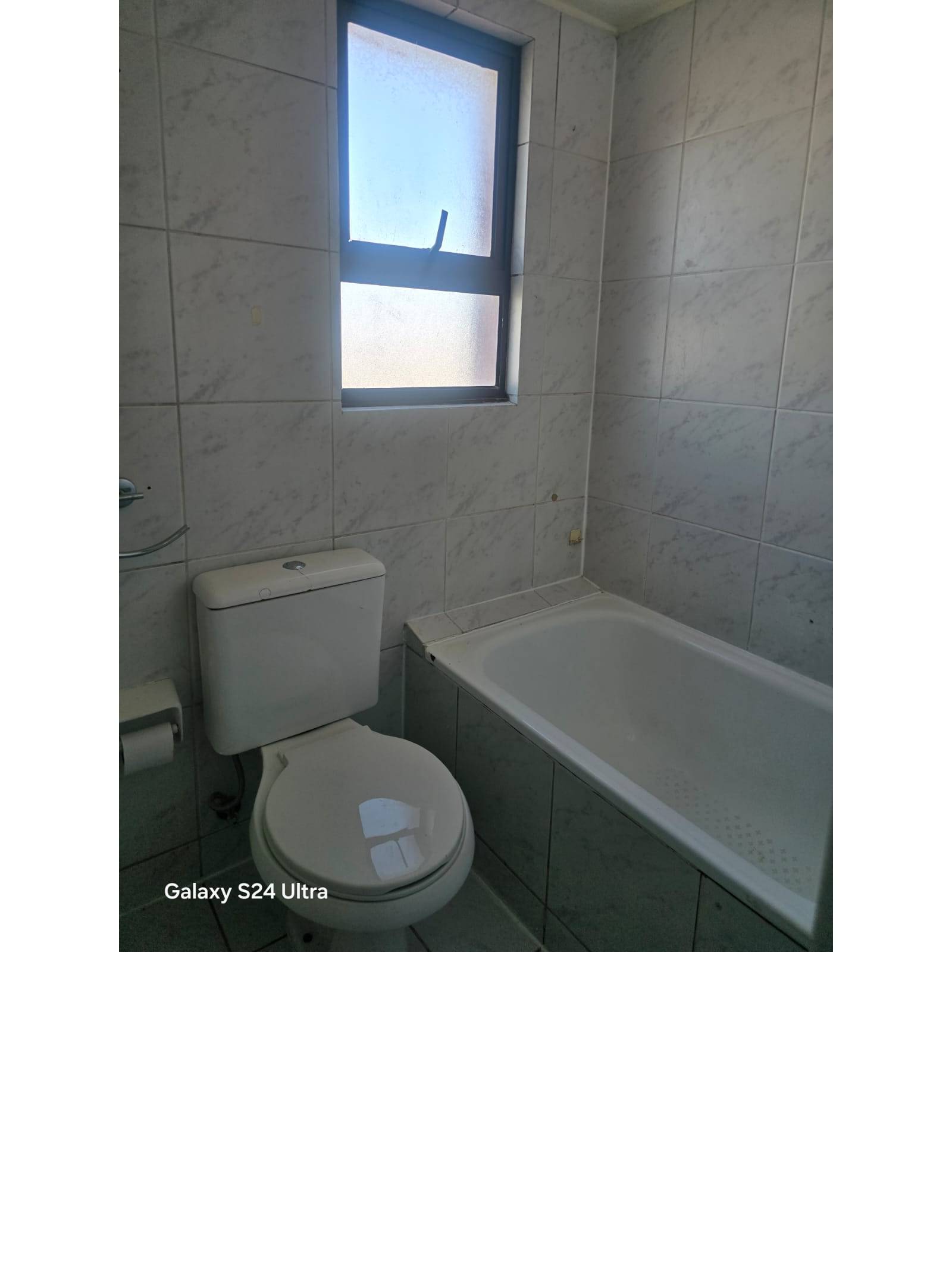 Tina y sanitario en baño iluminado con ventana alta