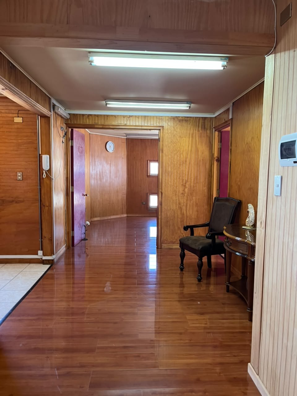 Hall de distribución con pisos de madera y luminarias fluorescentes