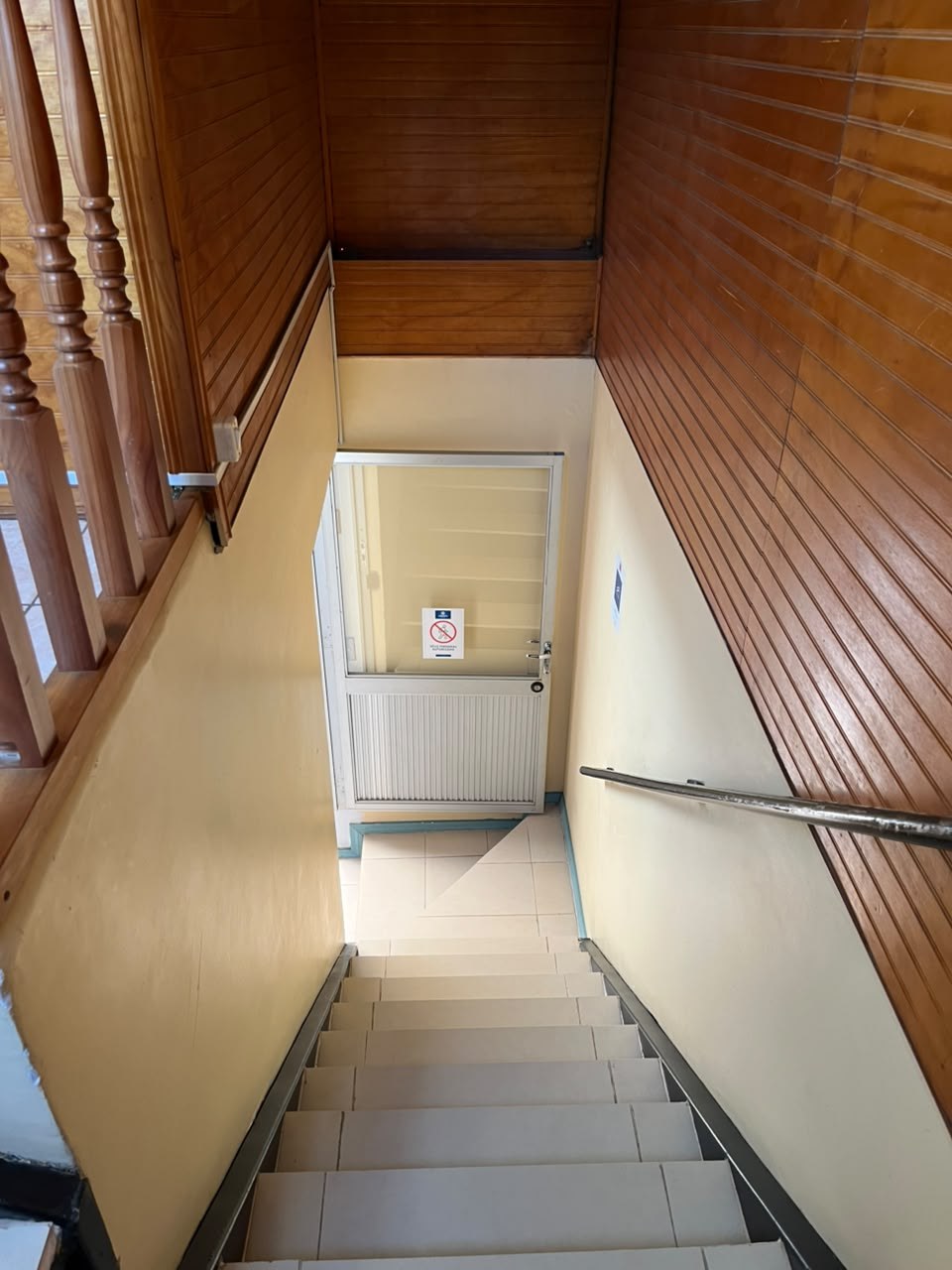 Escalera interior que desciende hacia puerta vidriada