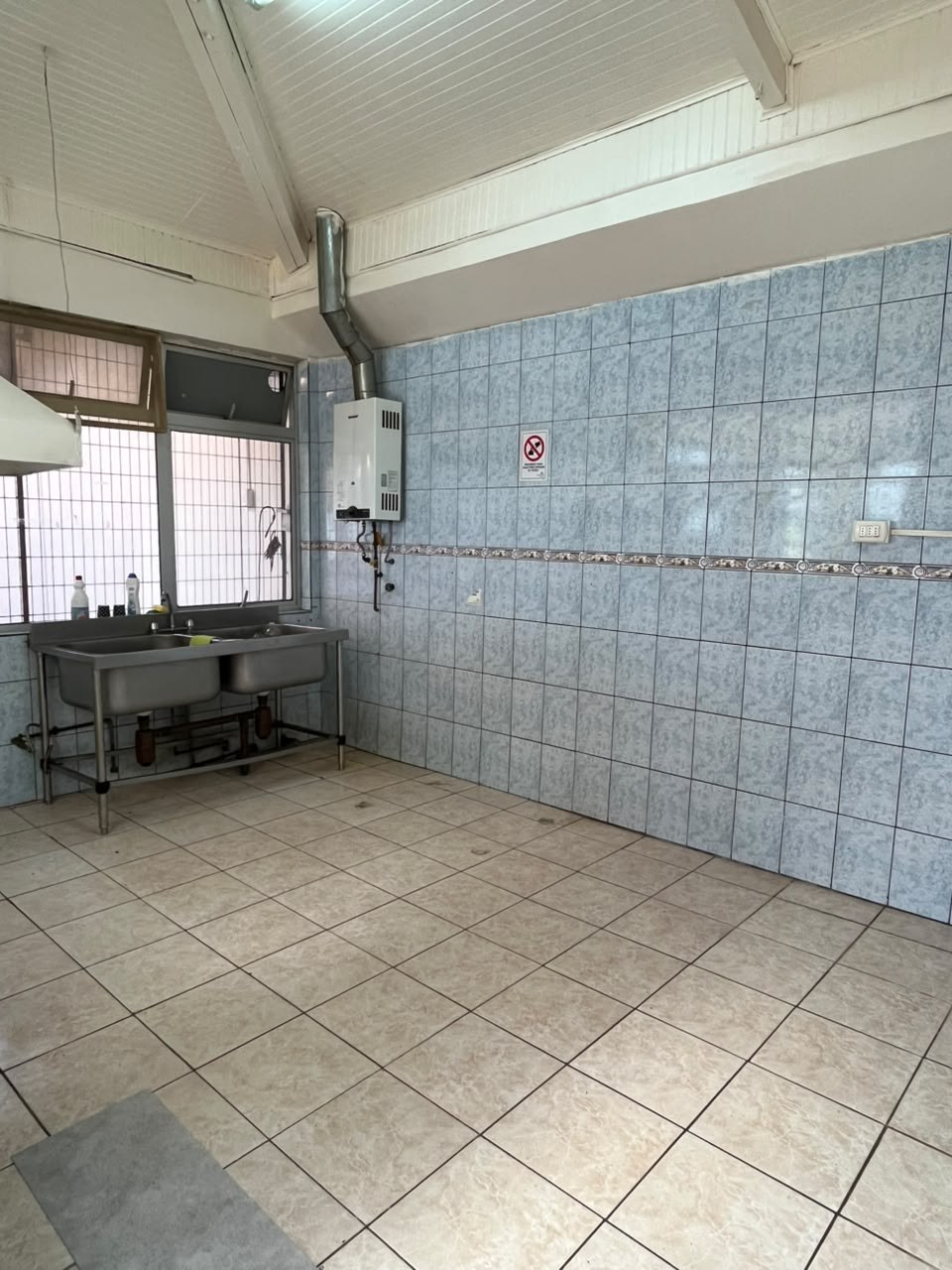 Cocina amplia con lavaplatos industrial y paredes completamente azulejadas