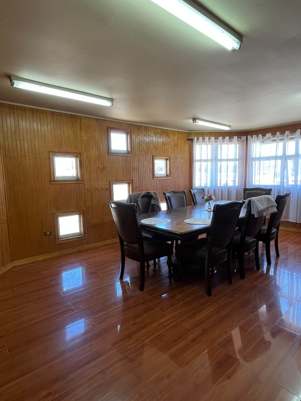 Comedor espacioso con gran mesa de reuniones y revestimientos de madera