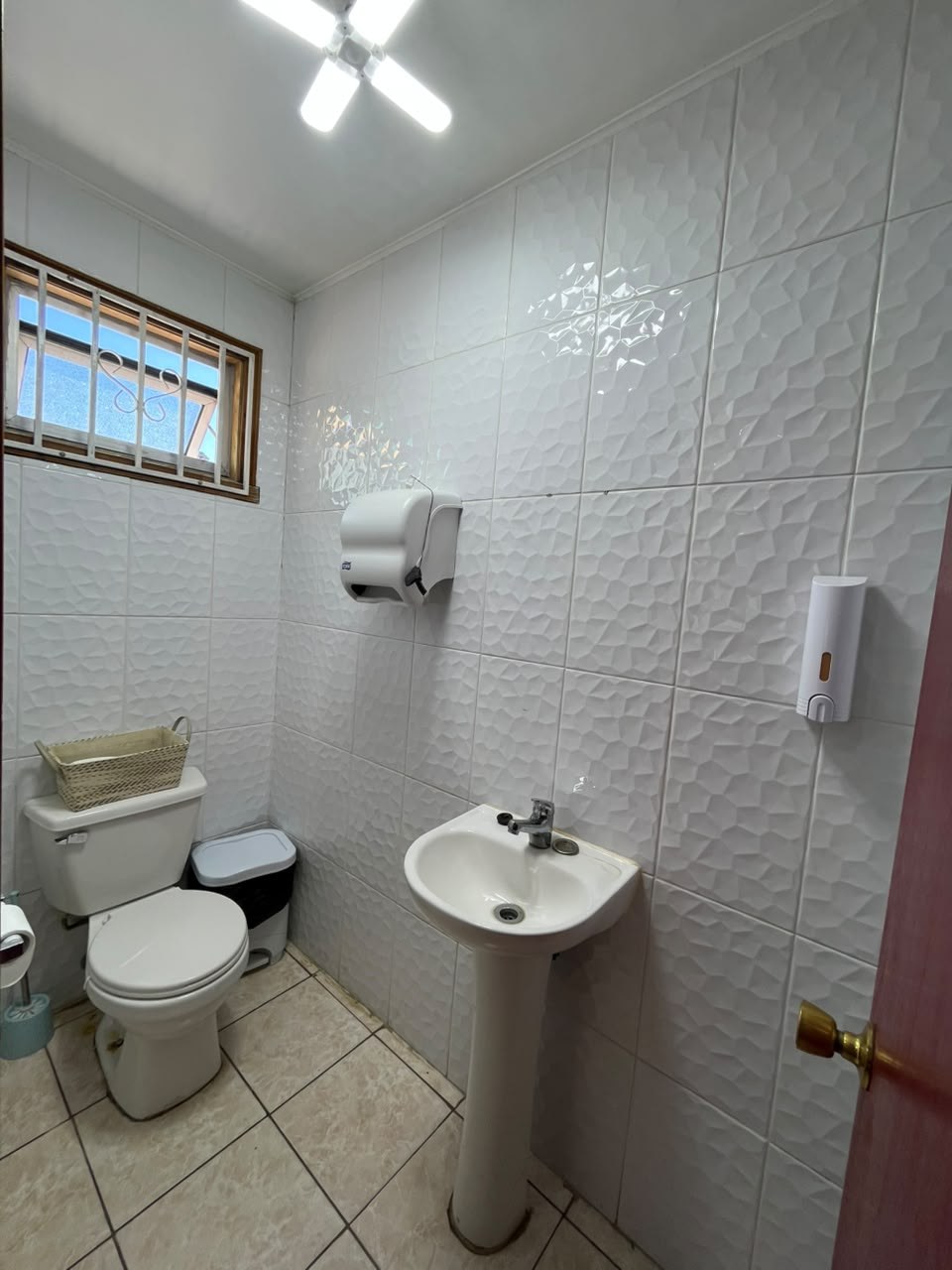 Baño con inodoro, lavamanos de pedestal y paredes con azulejos blancos