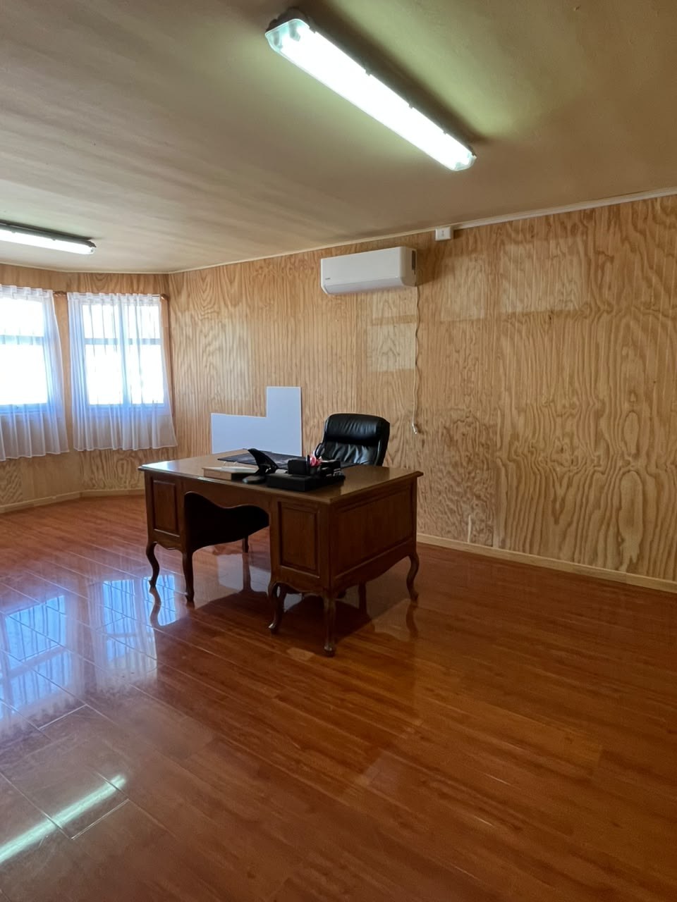 Oficina privada o dormitorio amplio con escritorio de madera y aire acondicionado