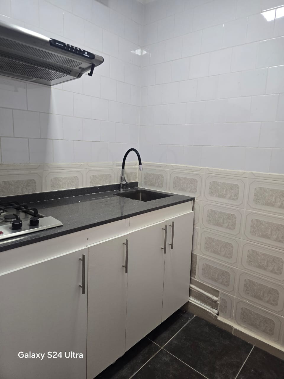Cocina con encimera de gas, campana y muebles bajo mesada