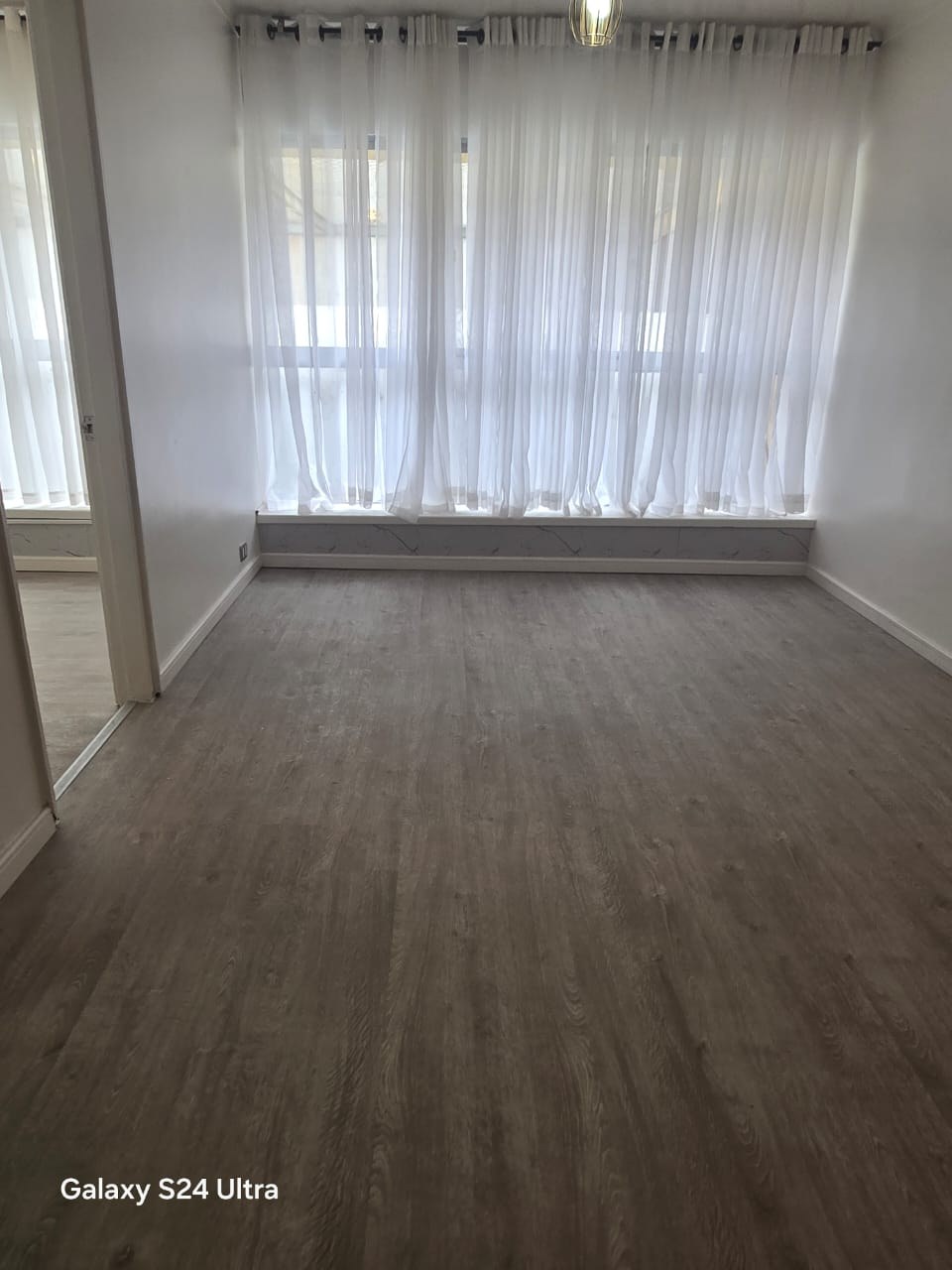 Living comedor con cortinas blancas y piso laminado