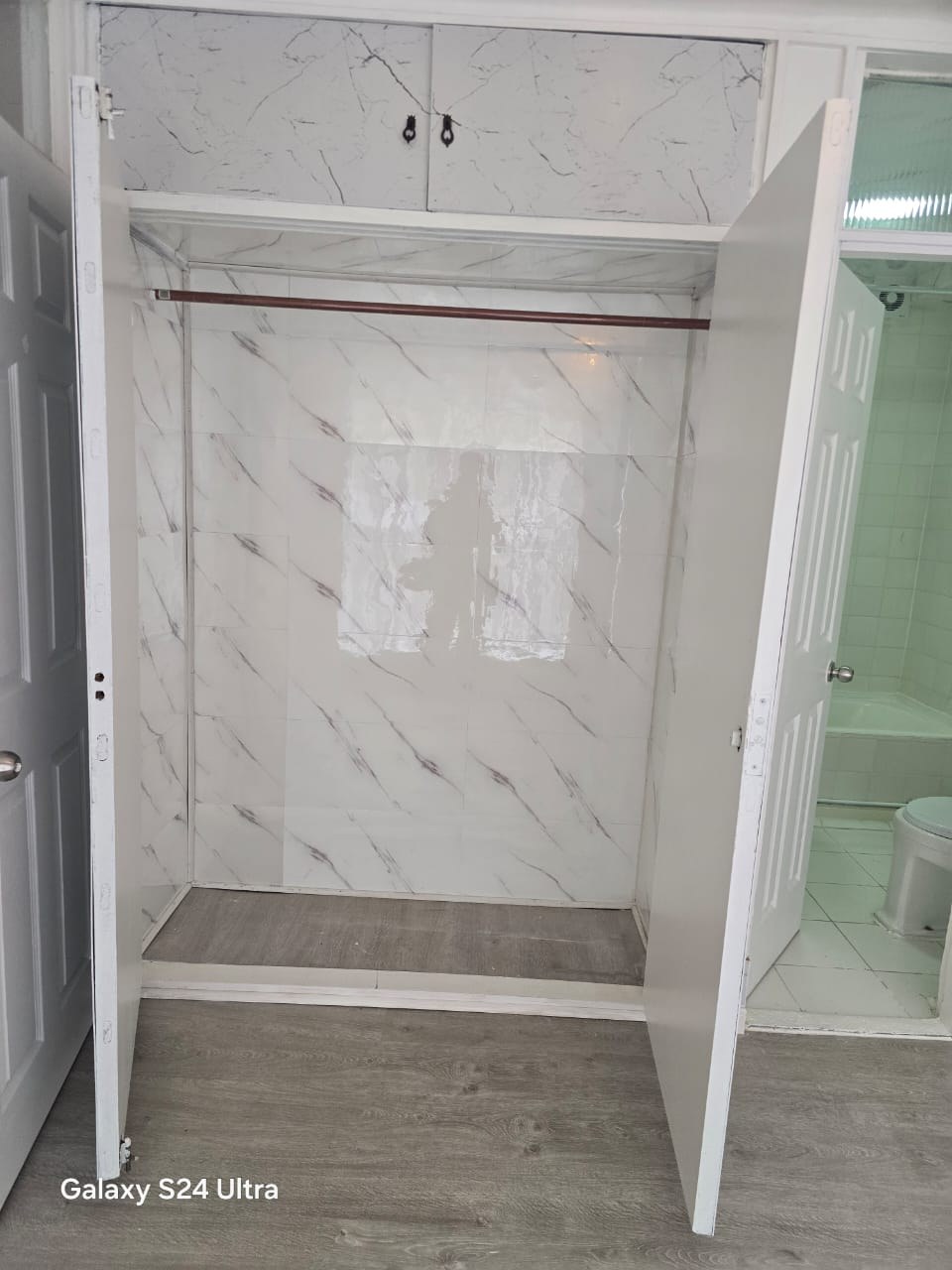 Interior de closet abierto en dormitorio con barra para colgar