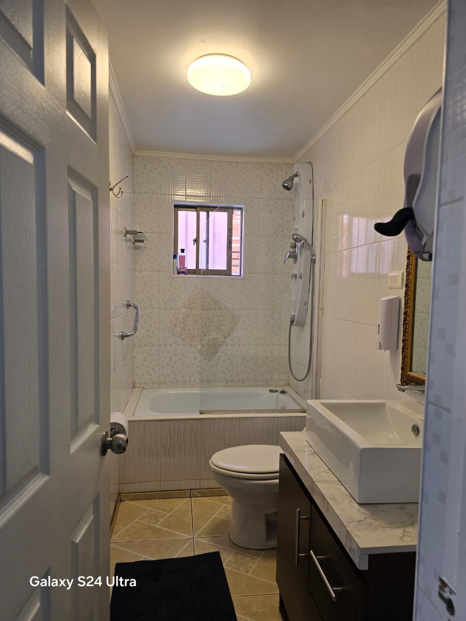 Baño completo con tina, vanitorio moderno y ventana exterior.