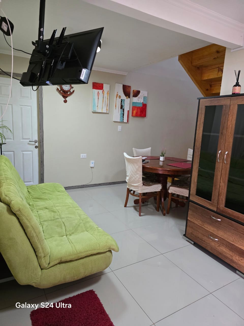 Living comedor con sillón verde y mesa redonda de madera.