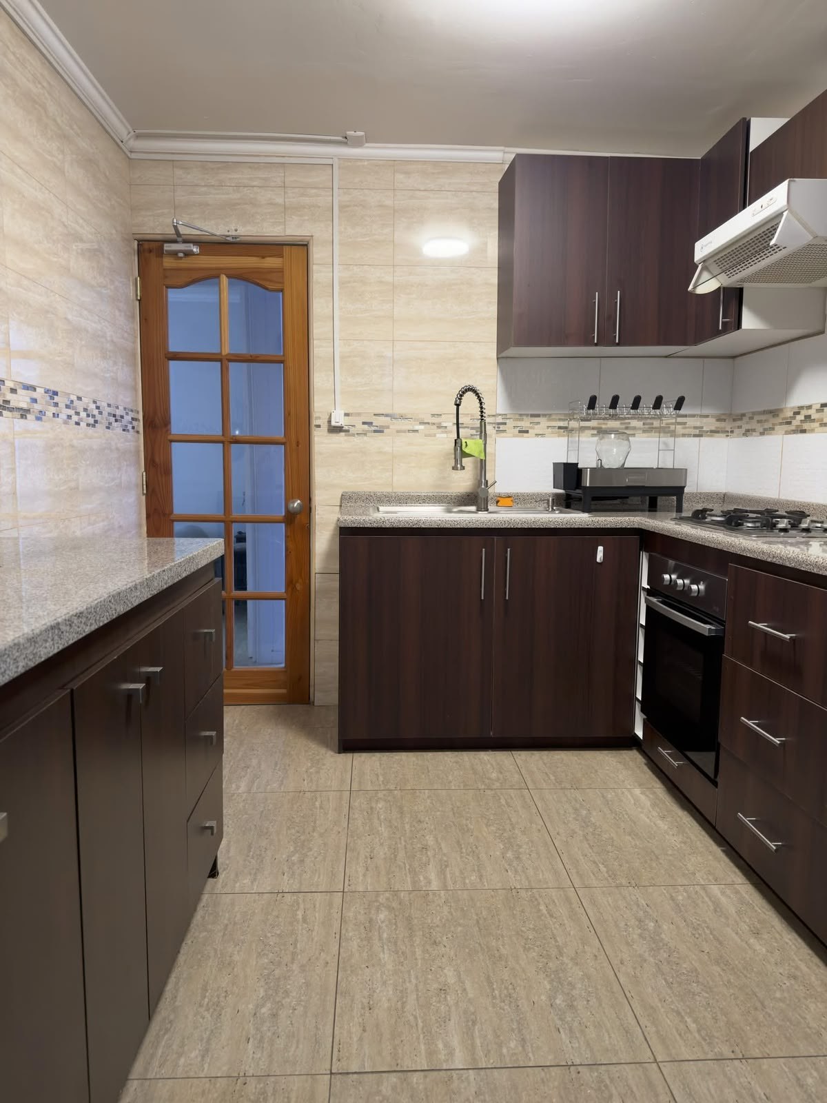 Cocina equipada con muebles oscuros, encimera y campana extractora.