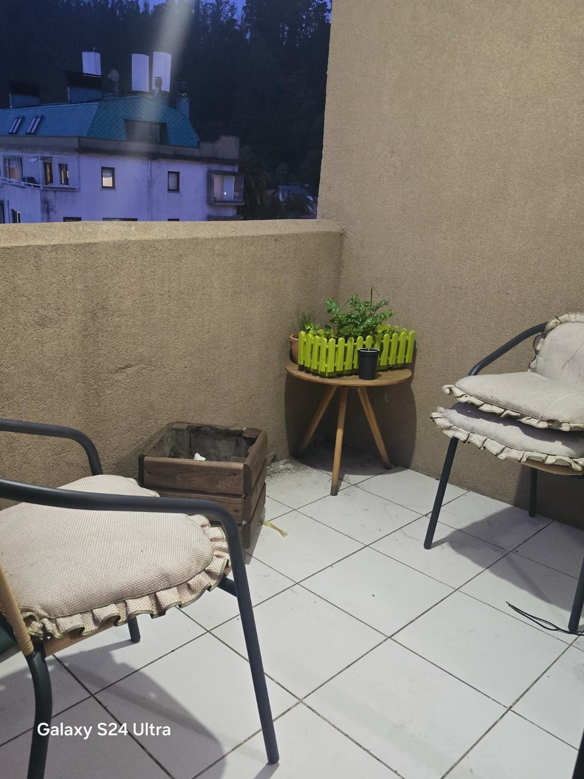 Terraza con piso cerámico, sillas de descanso y mesita esquinera