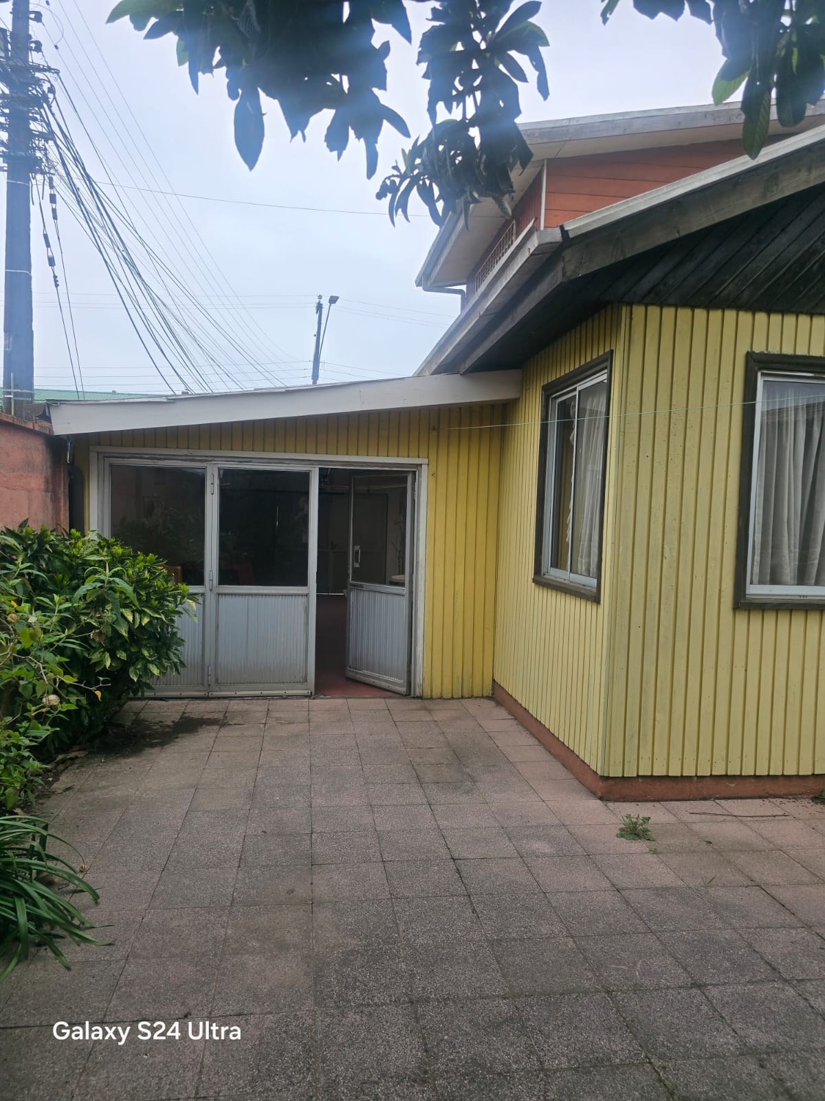 Patio trasero pavimentado junto a muros exteriores y ventanales