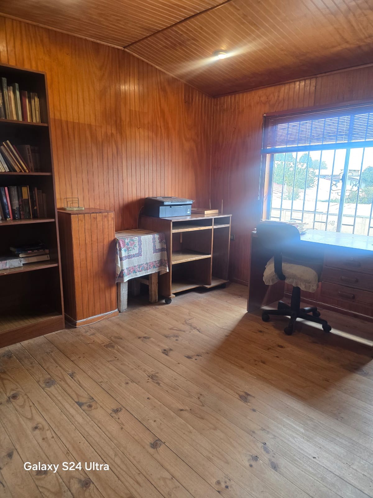 Habitación con paredes de madera, estante para libros y escritorio