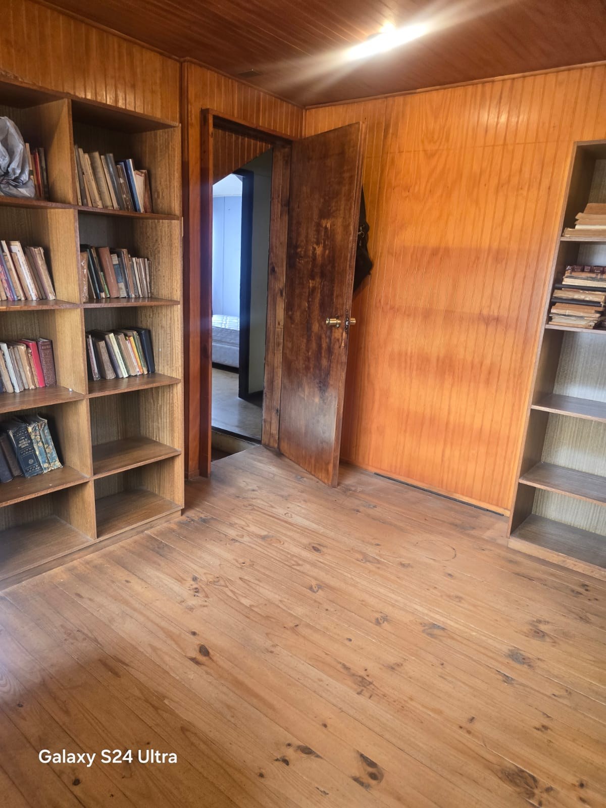 Pieza con estantes para libros empotrados y piso de madera