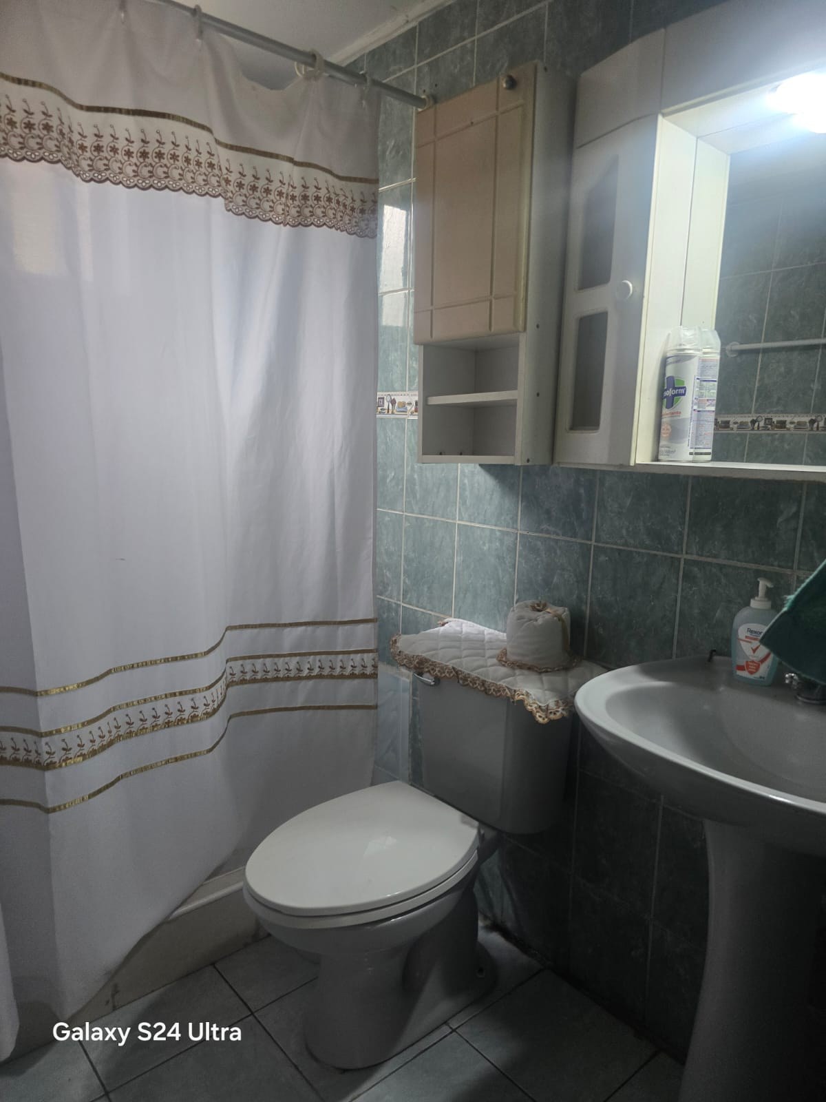 Baño con azulejos celestes, lavamanos de pedestal e inodoro