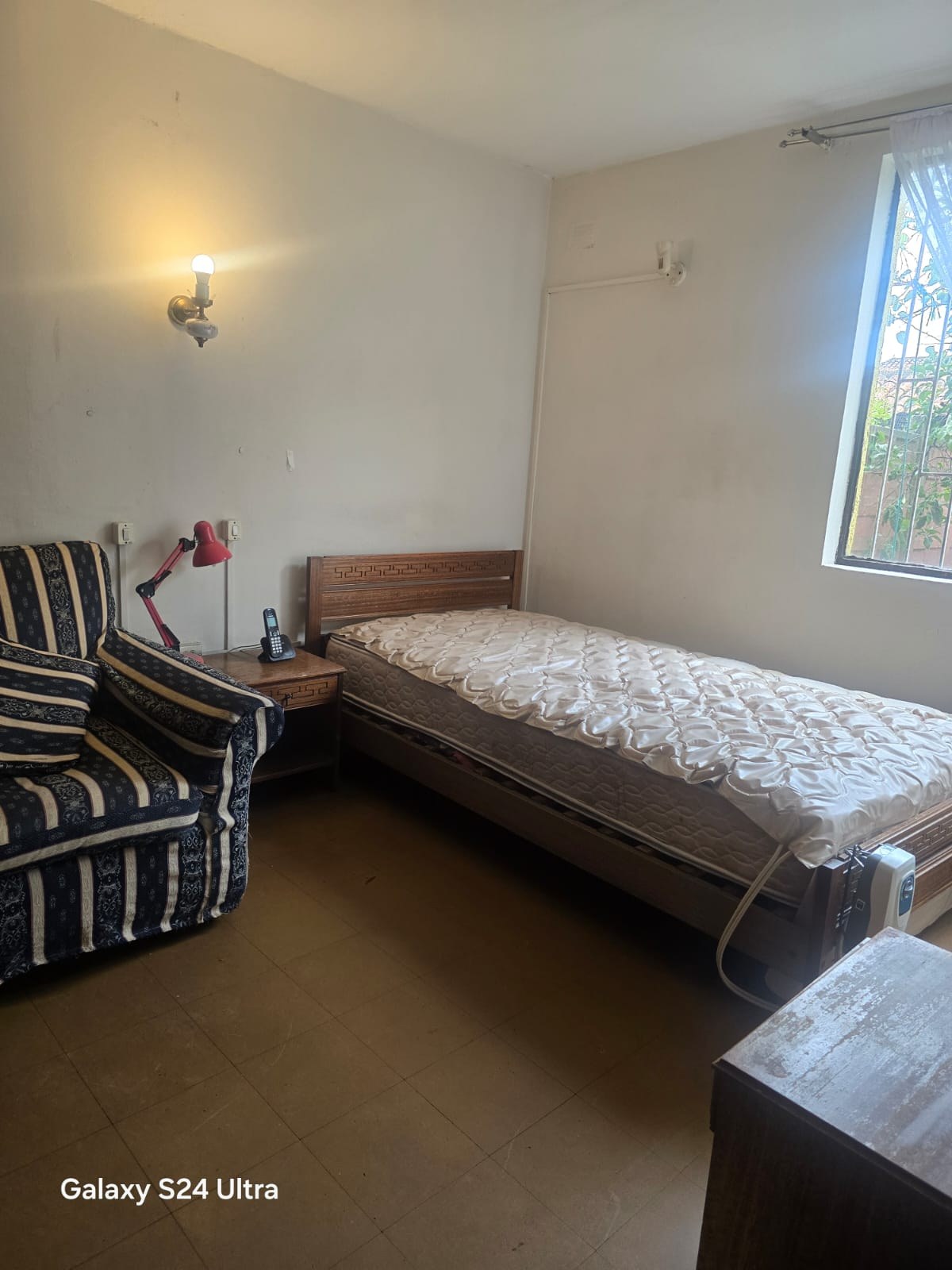 Dormitorio con cama de una plaza y sillón tapizado