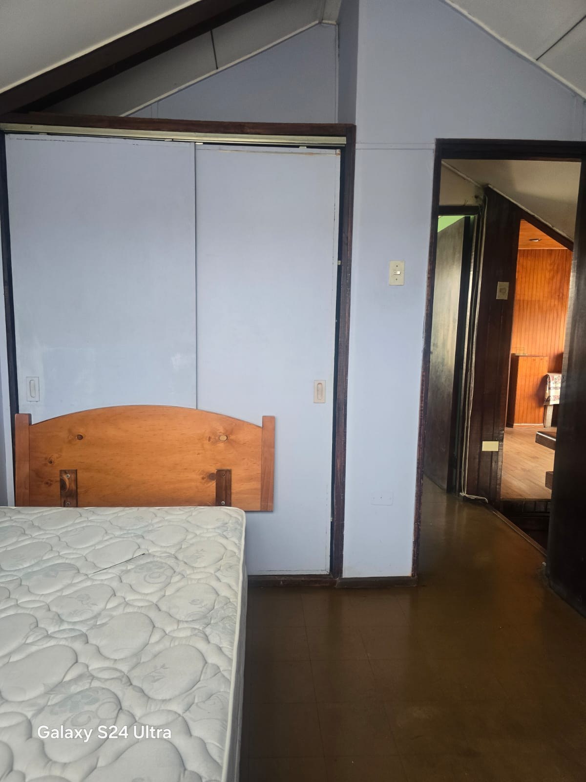 Habitación con clóset empotrado y cama con respaldo de madera