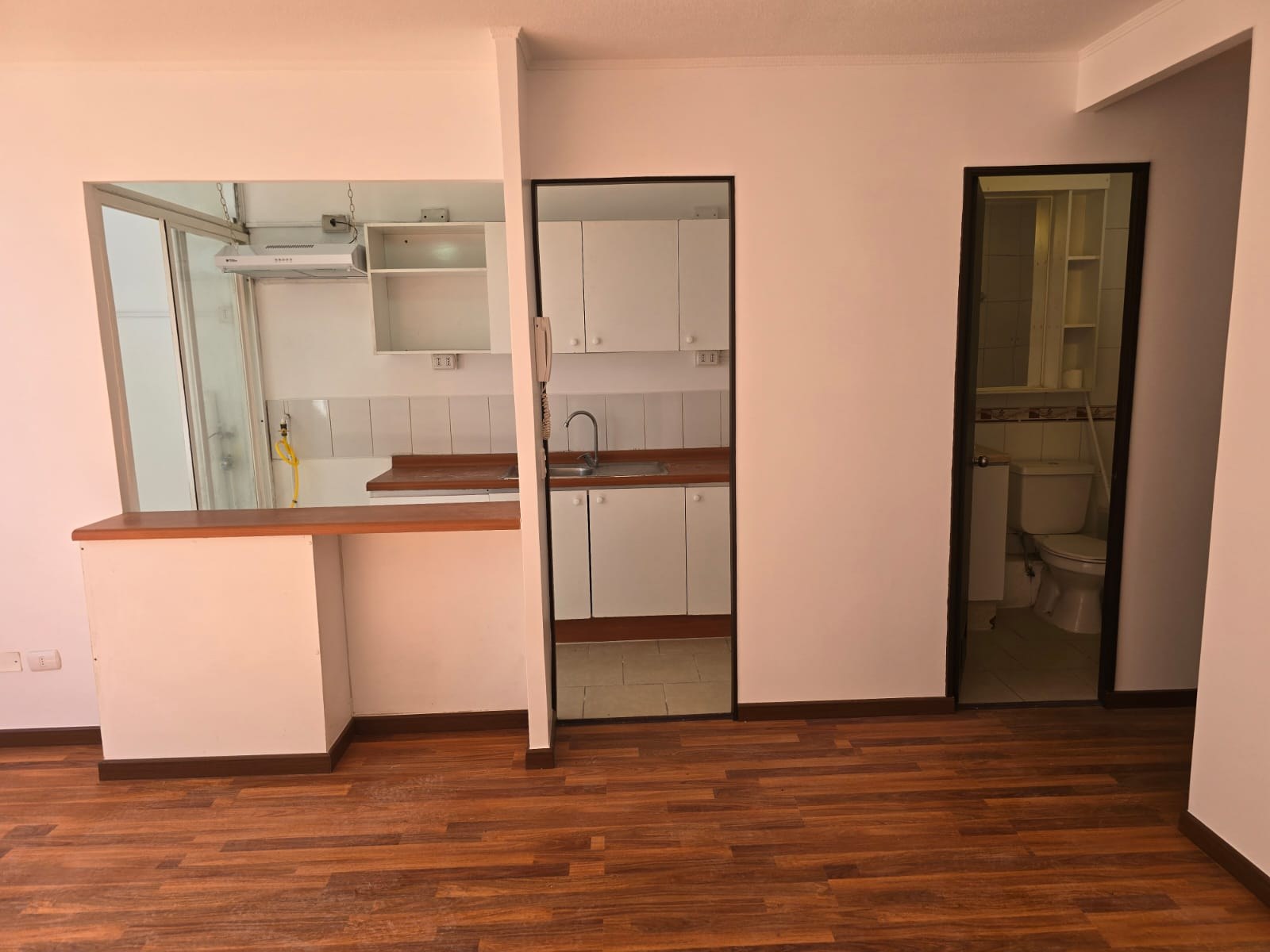 Vista frontal de cocina con barra y muebles empotrados.