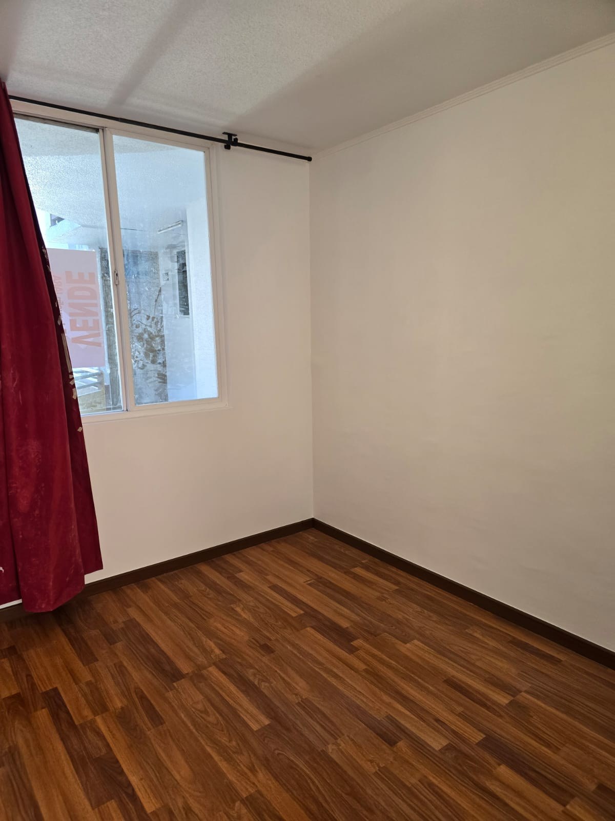 Dormitorio con piso flotante y ventana con cortina.