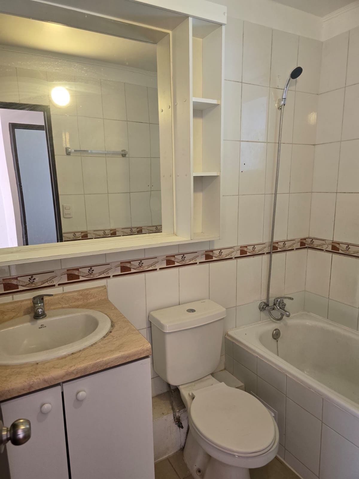 Baño completo con tina, inodoro y vanitorio con botiquín.