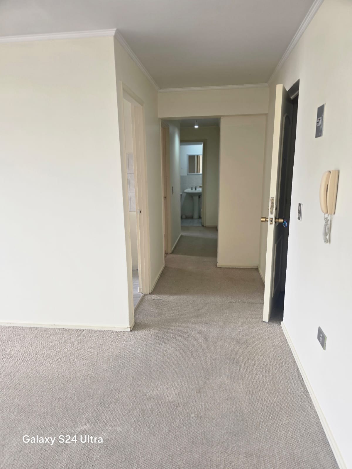 Hall de distribución alfombrado hacia dormitorios y baño