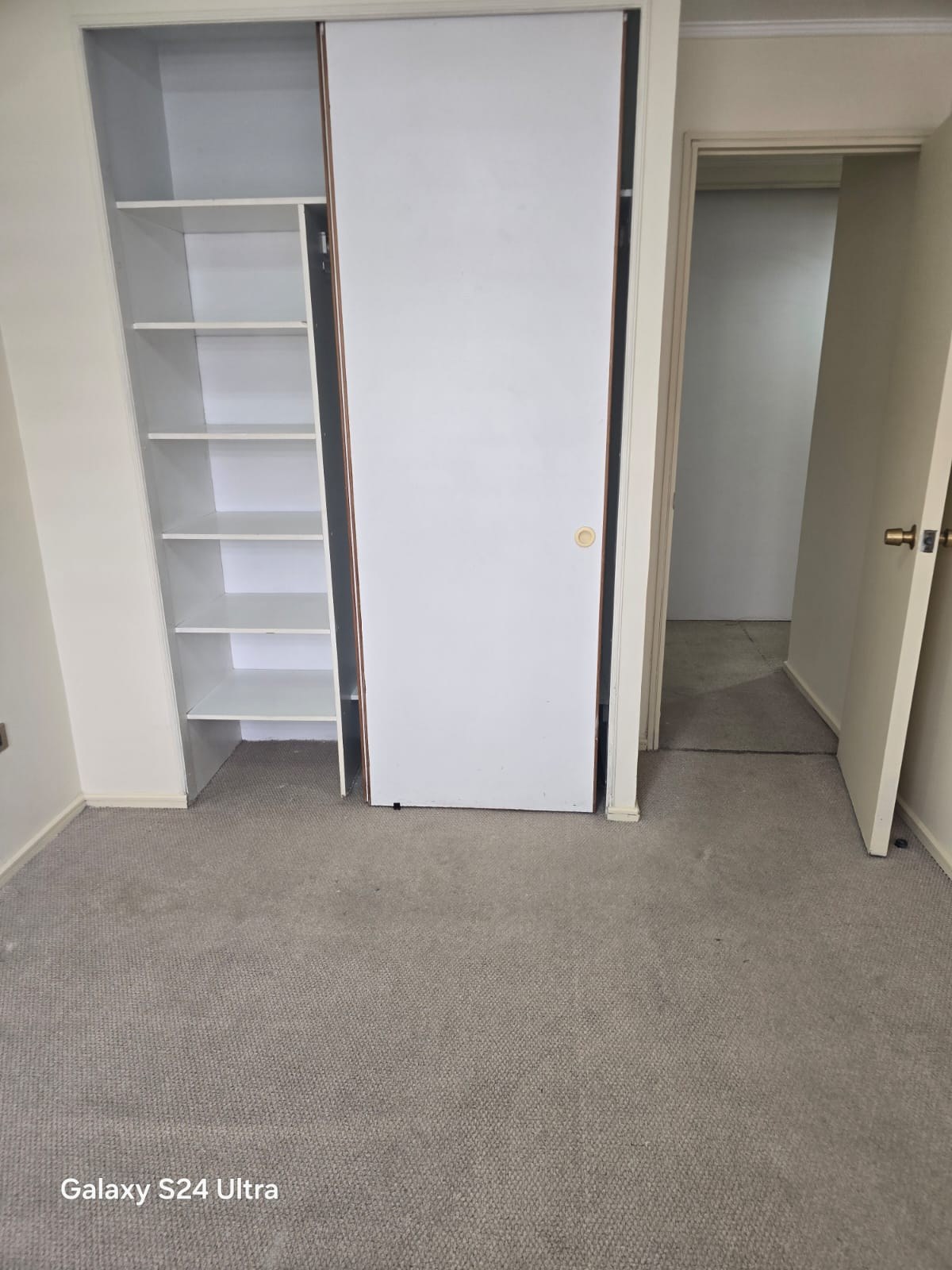 Clóset integrado con repisas abiertas y puerta corredera blanca