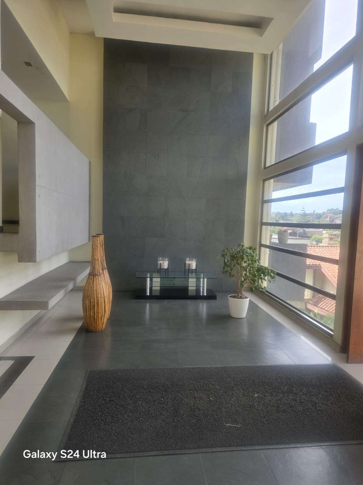 Recepción del edificio con ventanal amplio y muro de piedra