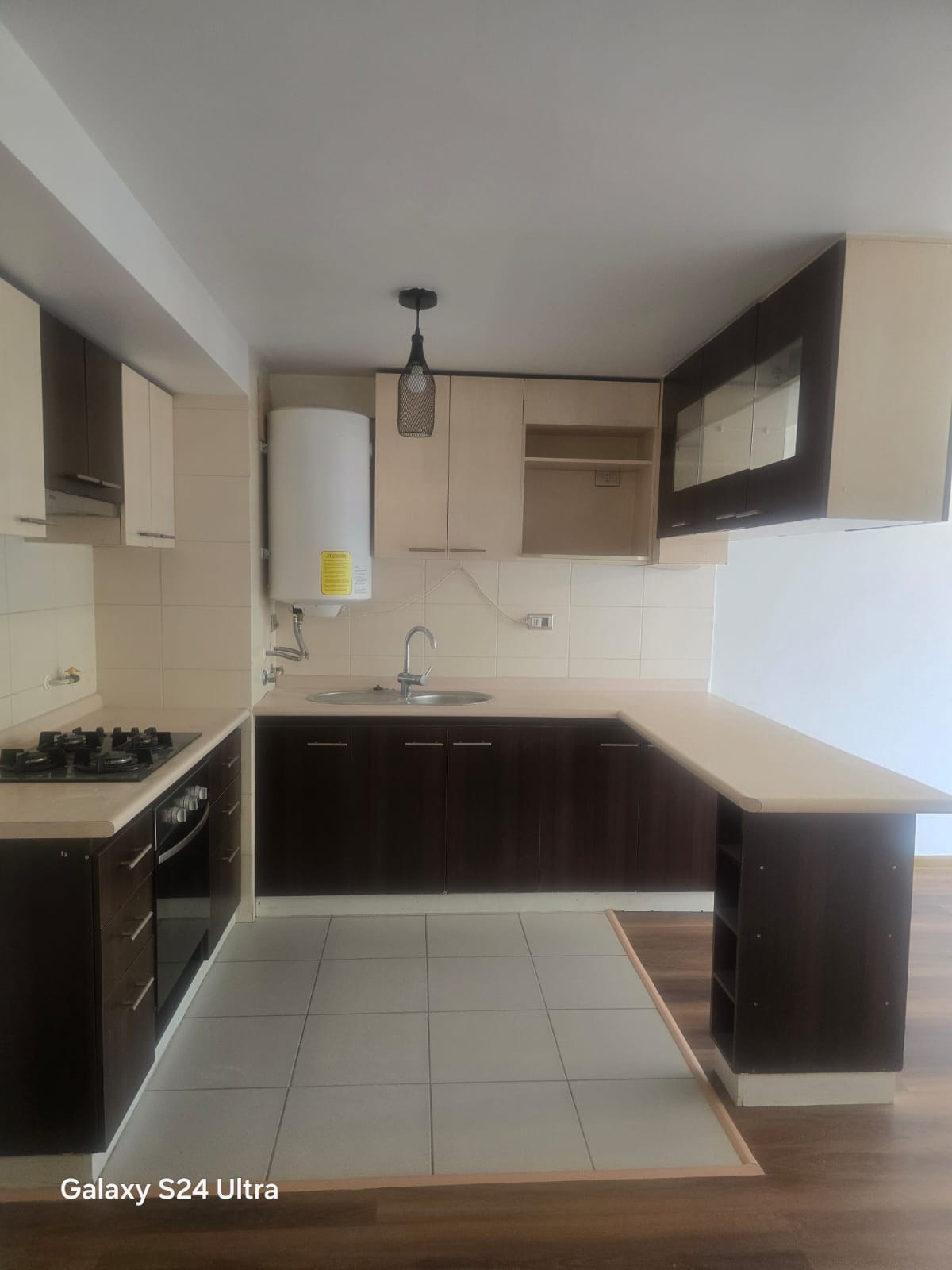 Cocina equipada con encimera muebles altos y barra desayunadora