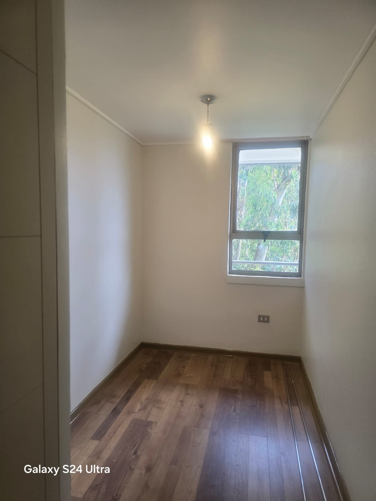 Dormitorio vacío con piso flotante y ventana al exterior