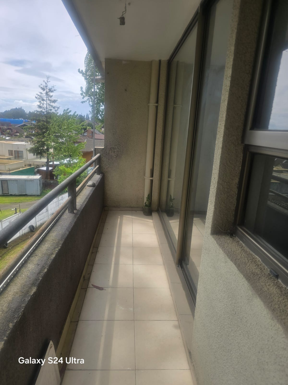 Terraza alargada con piso cerámico y vista hacia el entorno