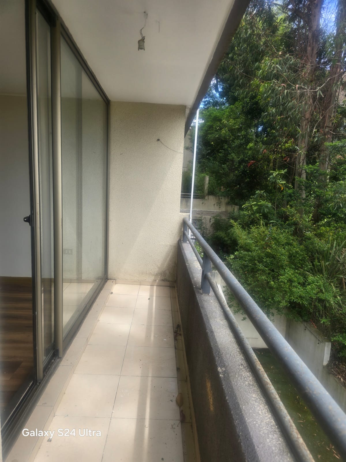 Balcón exterior con baranda y vista a árboles circundantes