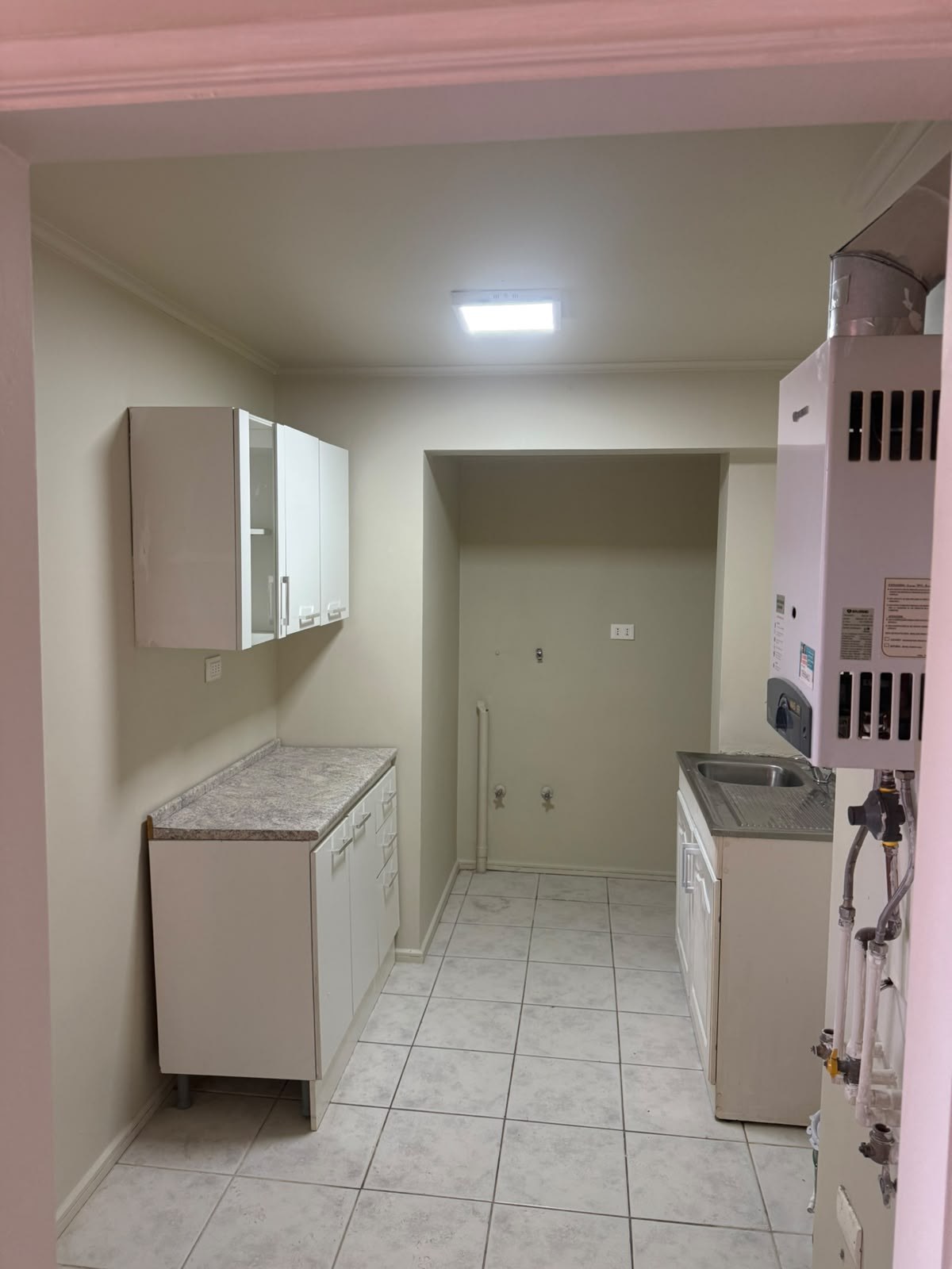 Cocina con muebles base y aéreos, lavaplatos y calefón